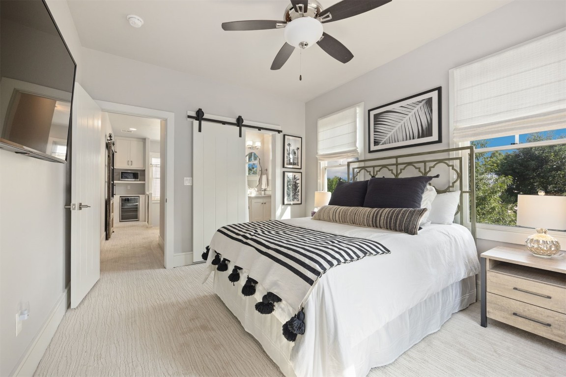 53 Boardwalk Street, Carlton Landing, OK 74432 bedroom featuring light colored carpet, ceiling fan, wine cooler, and a barn door