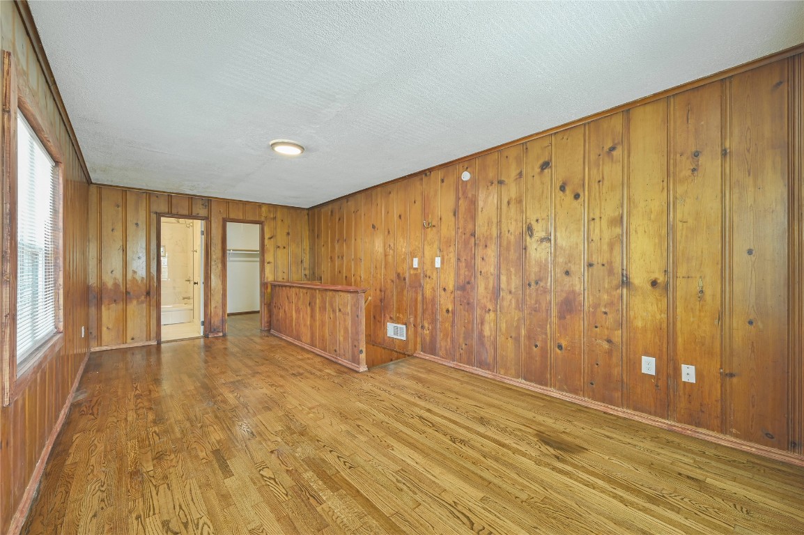 3013 SW 28th Street, Oklahoma City, OK 73108 spare room with a textured ceiling, light hardwood / wood-style floors, and wooden walls