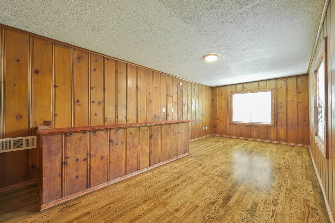 3013 SW 28th Street, Oklahoma City, OK 73108 unfurnished room with wooden walls, a textured ceiling, and light wood-type flooring
