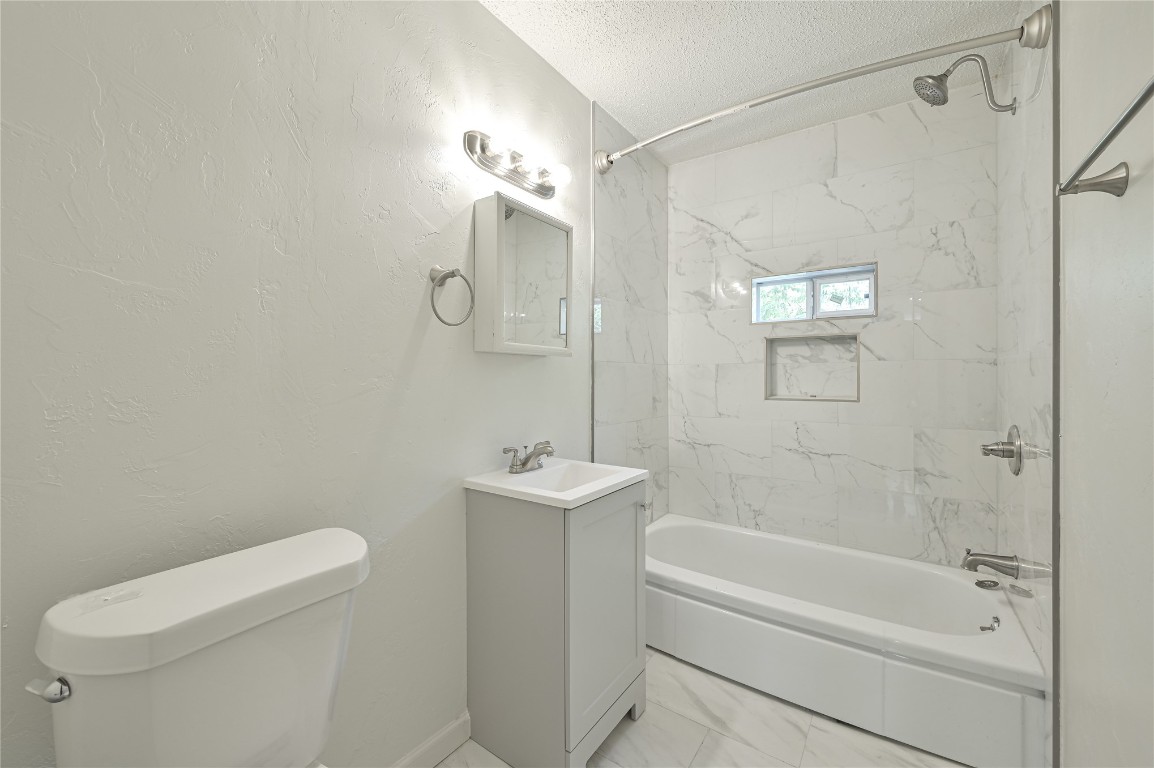 3013 SW 28th Street, Oklahoma City, OK 73108 full bathroom with tile flooring, tiled shower / bath combo, a textured ceiling, toilet, and vanity