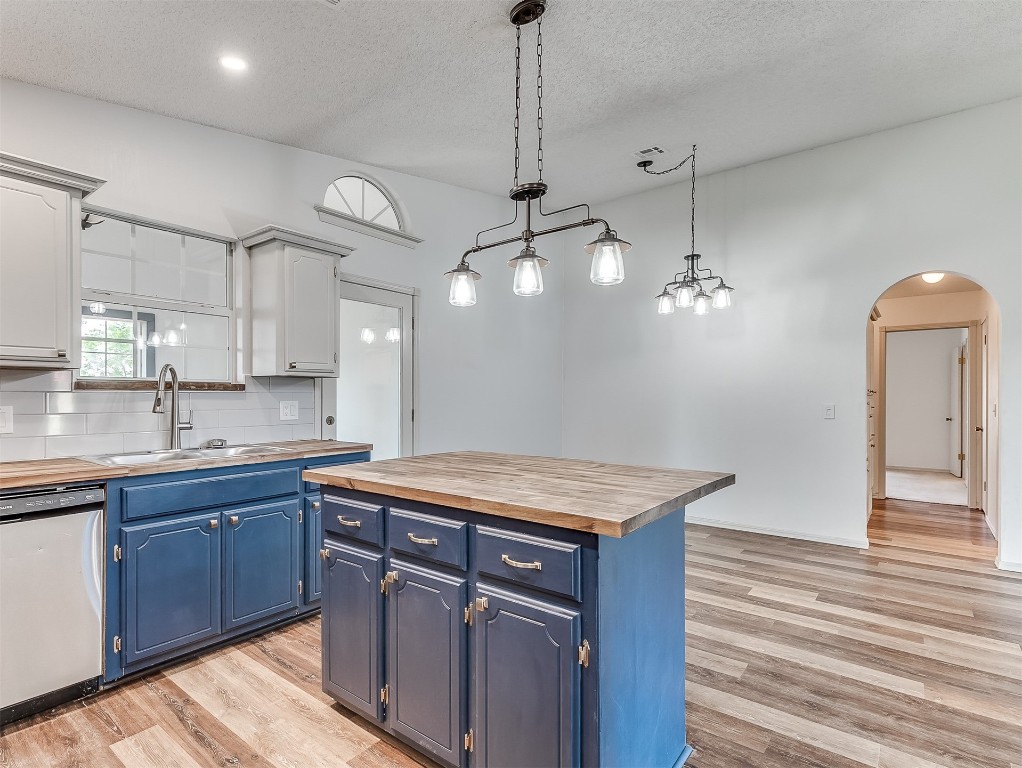 935 W Ridgehaven Way, Mustang, OK 73064 kitchen featuring light hardwood / wood-style floors, tasteful backsplash, wood counters, blue cabinets, and stainless steel dishwasher