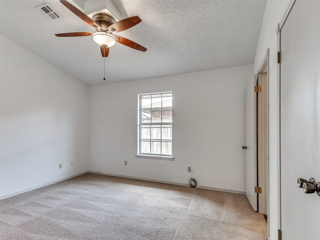 935 W Ridgehaven Way, Mustang, OK 73064 empty room with light carpet, ceiling fan, and a textured ceiling