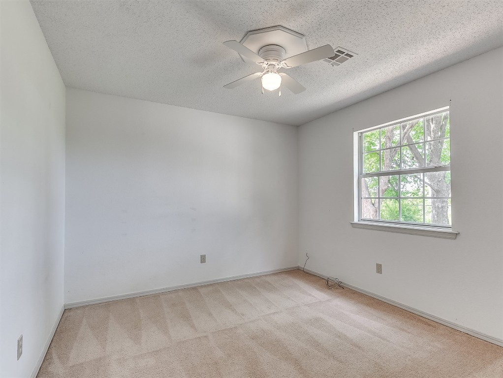 935 W Ridgehaven Way, Mustang, OK 73064 empty room featuring light colored carpet, a textured ceiling, and ceiling fan