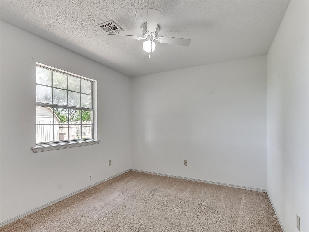 935 W Ridgehaven Way, Mustang, OK 73064 carpeted spare room with ceiling fan and a textured ceiling