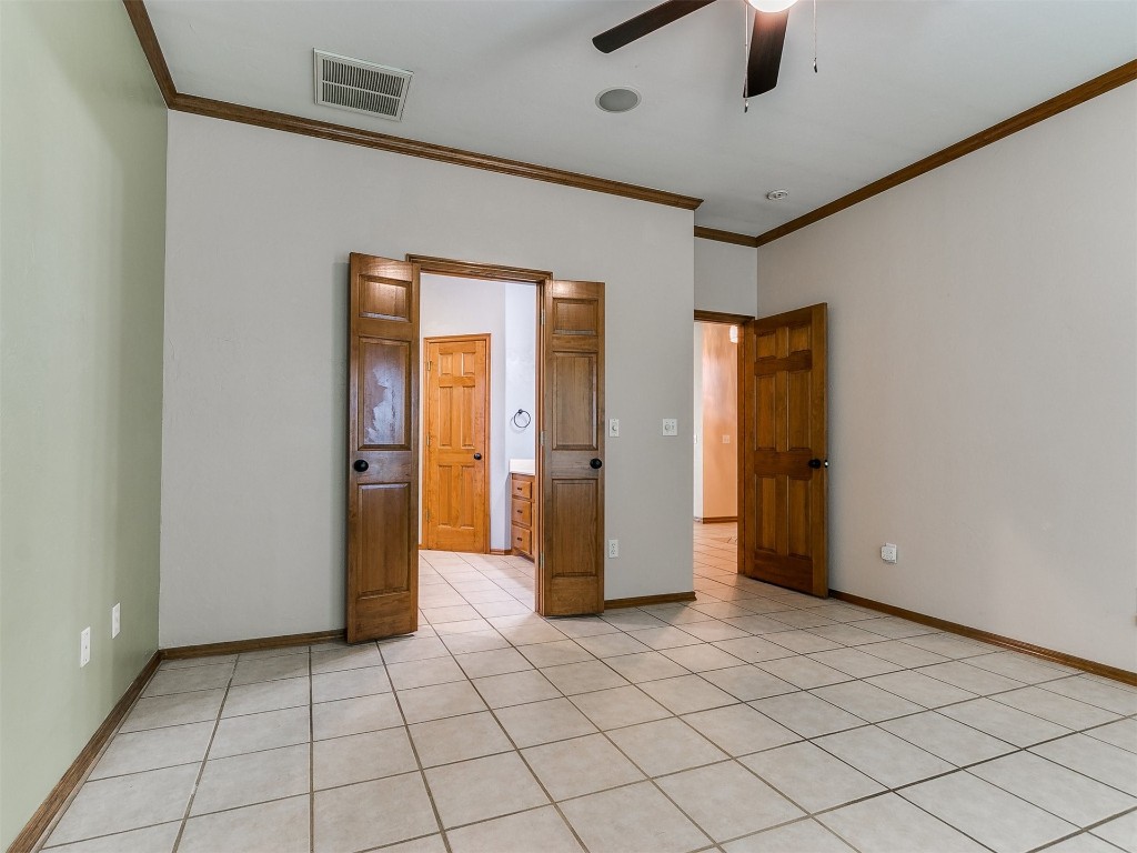 1400 NW 9th Street, Moore, OK 73170 unfurnished bedroom with ceiling fan, crown molding, and light tile floors
