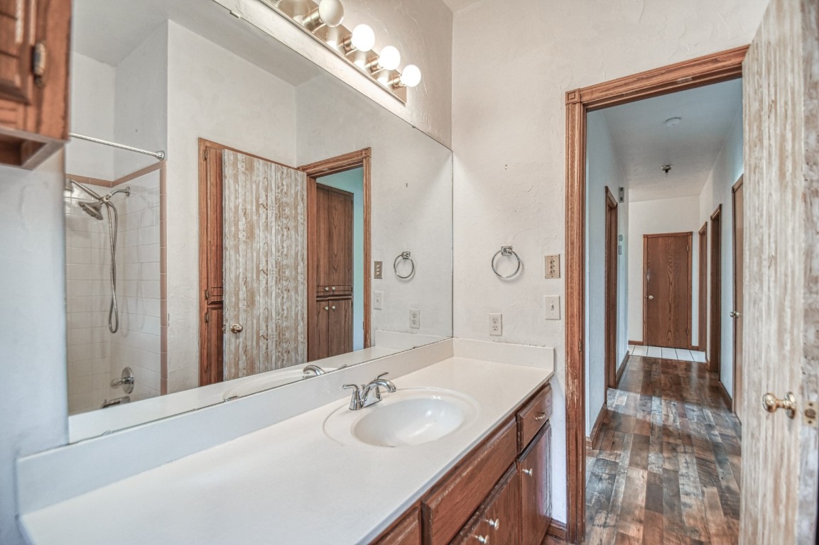 1725 Ryan Way, Edmond, OK 73003 bathroom with tub / shower combination, oversized vanity, and hardwood / wood-style floors