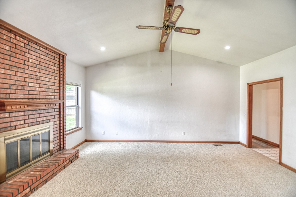 1725 Ryan Way, Edmond, OK 73003 unfurnished living room featuring light colored carpet, a brick fireplace, ceiling fan, and lofted ceiling
