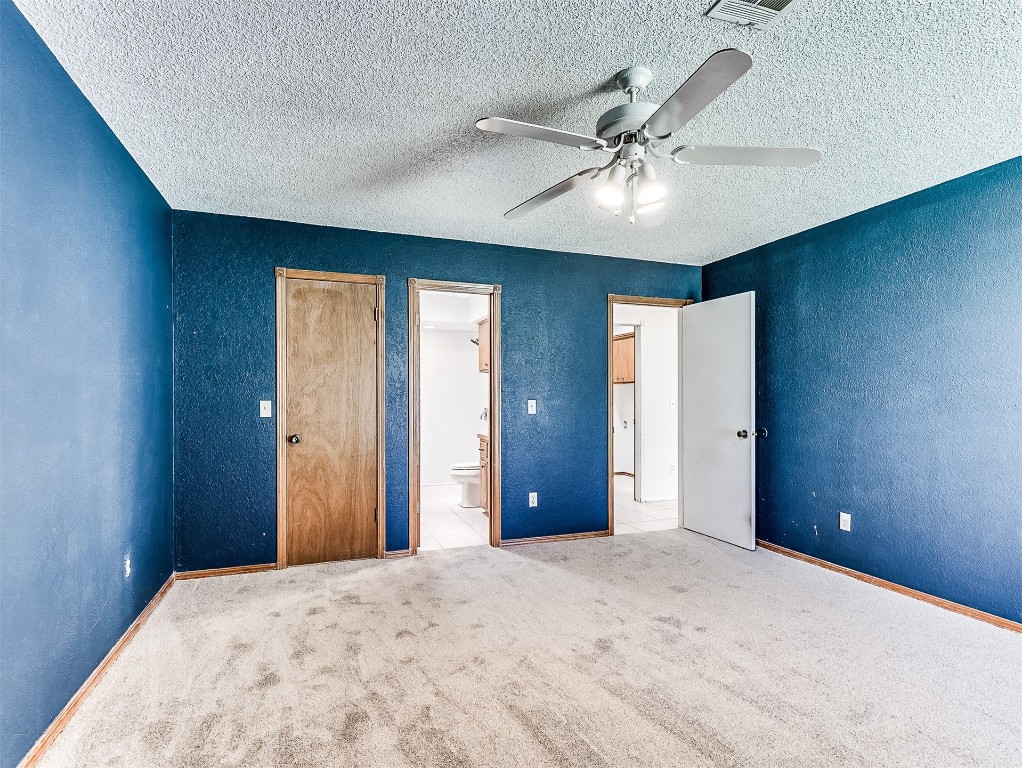 10525 Reiter Drive, Midwest City, OK 73130 unfurnished bedroom featuring ceiling fan, ensuite bath, carpet floors, and a textured ceiling