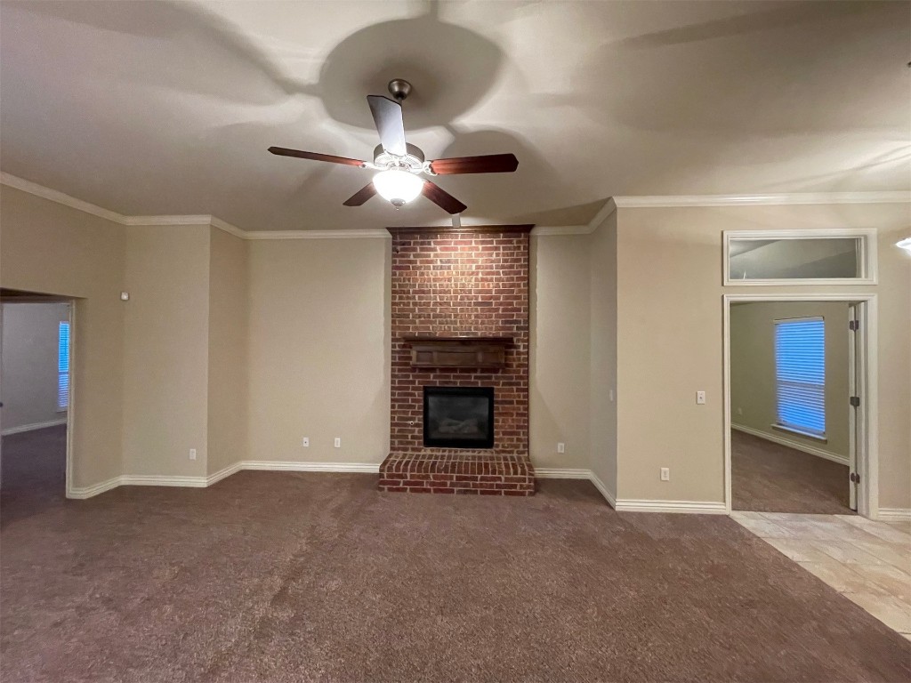 317 Durkee Road, Yukon, OK 73099 unfurnished living room featuring a fireplace, ceiling fan, carpet, and brick wall