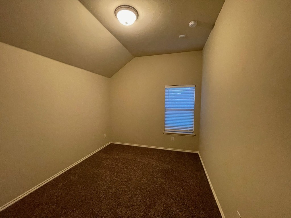 317 Durkee Road, Yukon, OK 73099 unfurnished room with dark colored carpet and vaulted ceiling