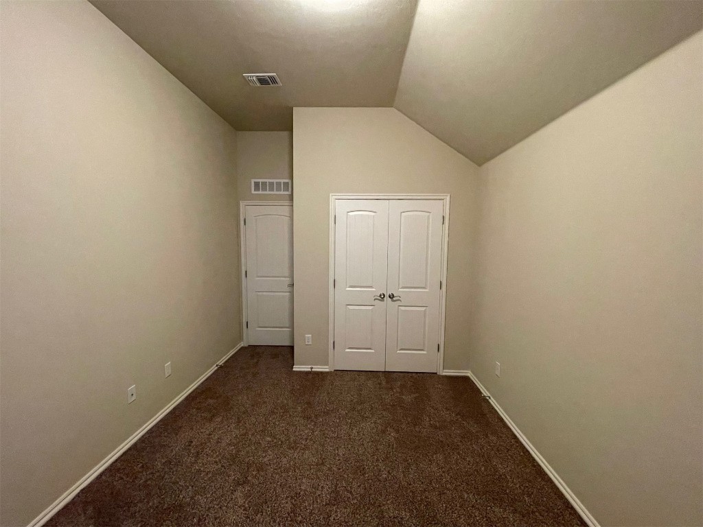 317 Durkee Road, Yukon, OK 73099 unfurnished bedroom with lofted ceiling, carpet flooring, and a closet