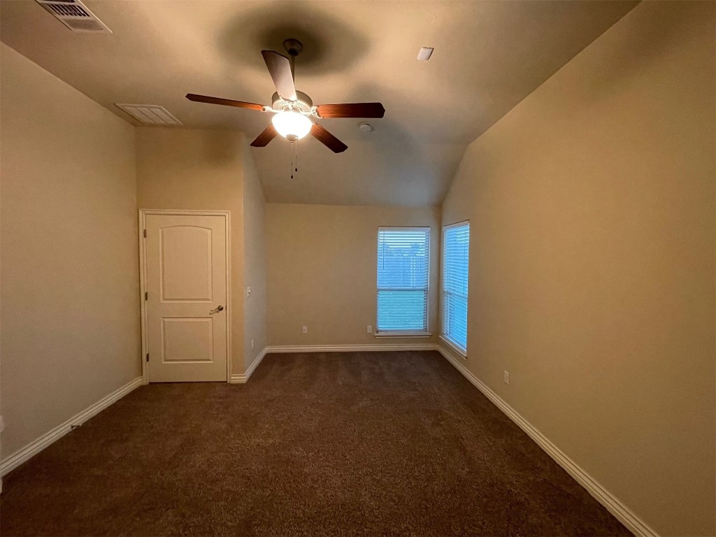 317 Durkee Road, Yukon, OK 73099 empty room featuring lofted ceiling, dark colored carpet, and ceiling fan