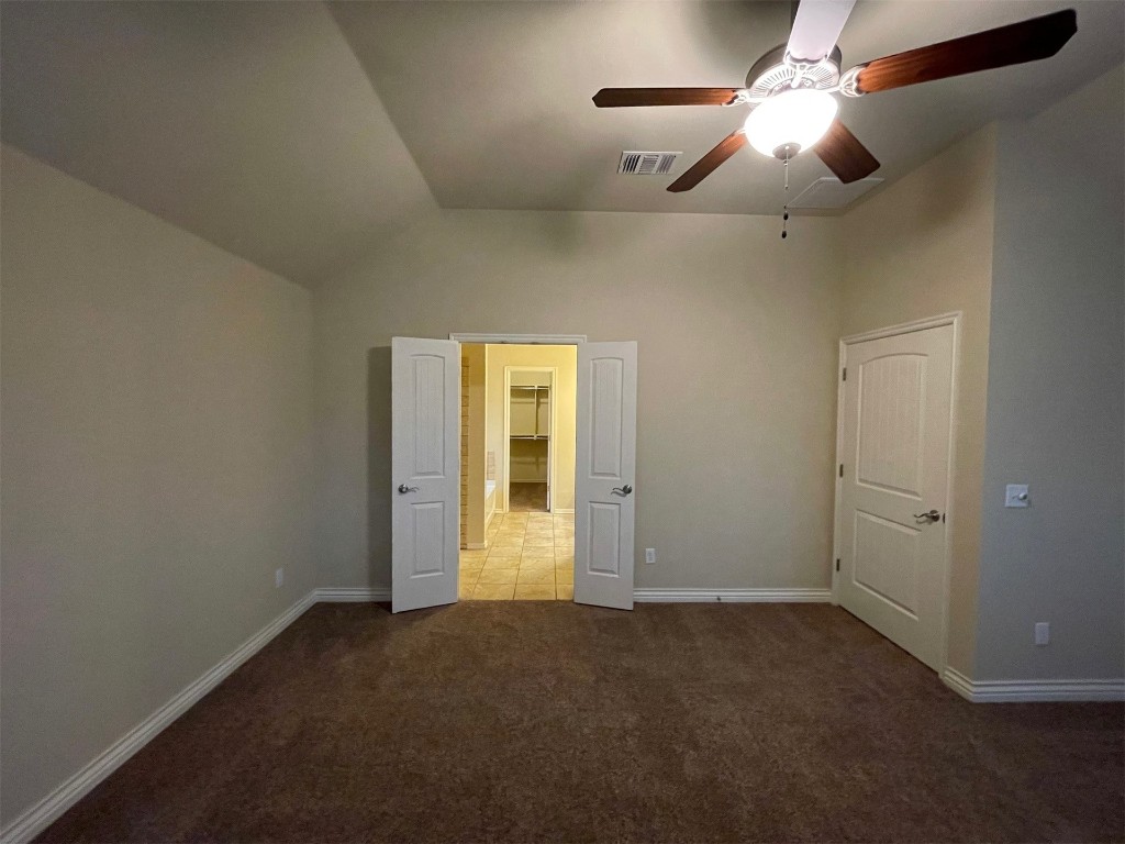 317 Durkee Road, Yukon, OK 73099 unfurnished bedroom with carpet flooring, a spacious closet, ceiling fan, and vaulted ceiling