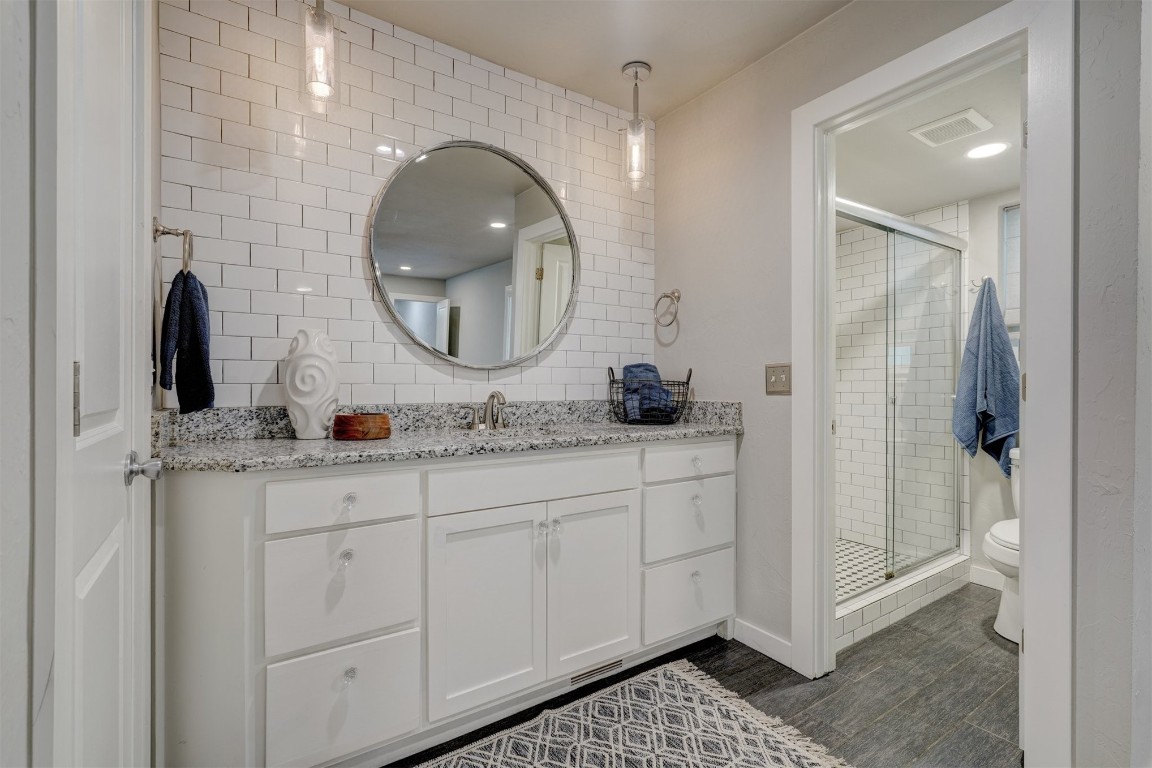 10112 Midfield Cross Street, Oklahoma City, OK 73159 bathroom with a shower with door, vanity, tile walls, tasteful backsplash, and toilet