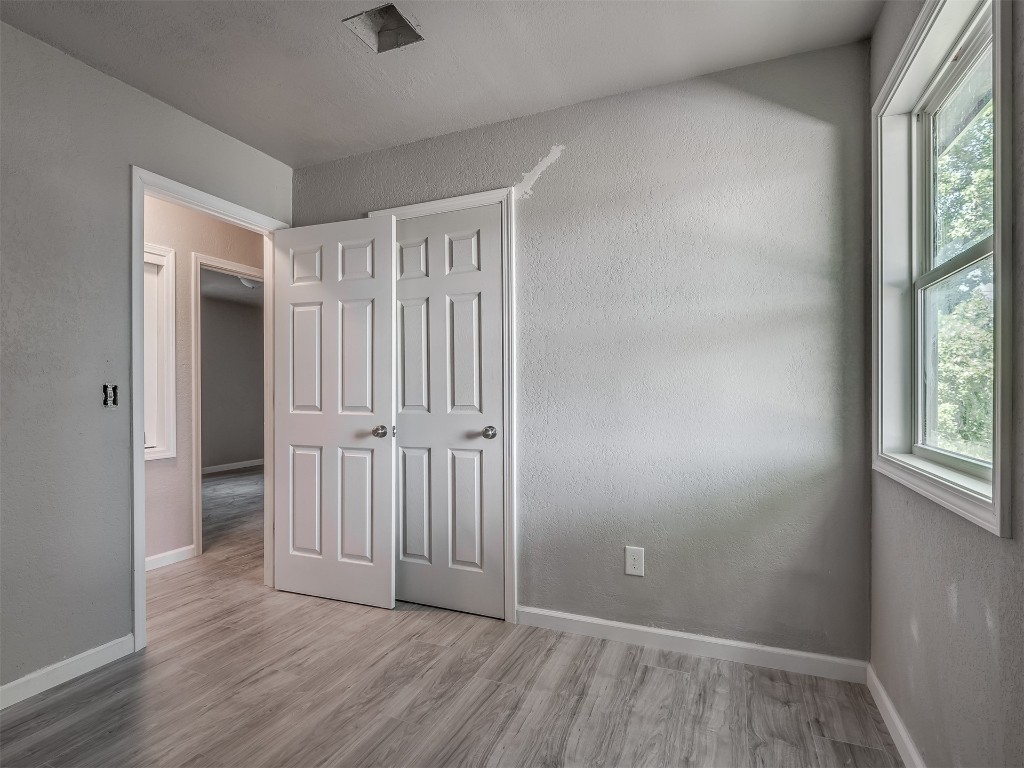801 NW 113th Street, Oklahoma City, OK 73114 unfurnished bedroom featuring hardwood / wood-style floors and multiple windows