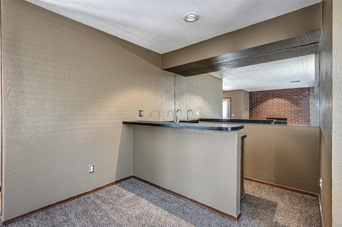 4400 Hemingway Drive, #242, Oklahoma City, OK 73118 kitchen with dark carpet, kitchen peninsula, and a textured ceiling
