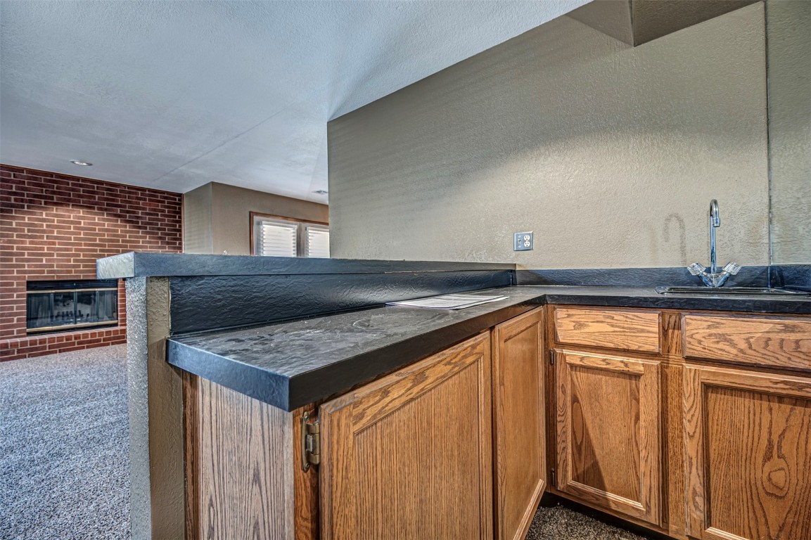 4400 Hemingway Drive, #242, Oklahoma City, OK 73118 kitchen featuring sink, kitchen peninsula, carpet, and a brick fireplace