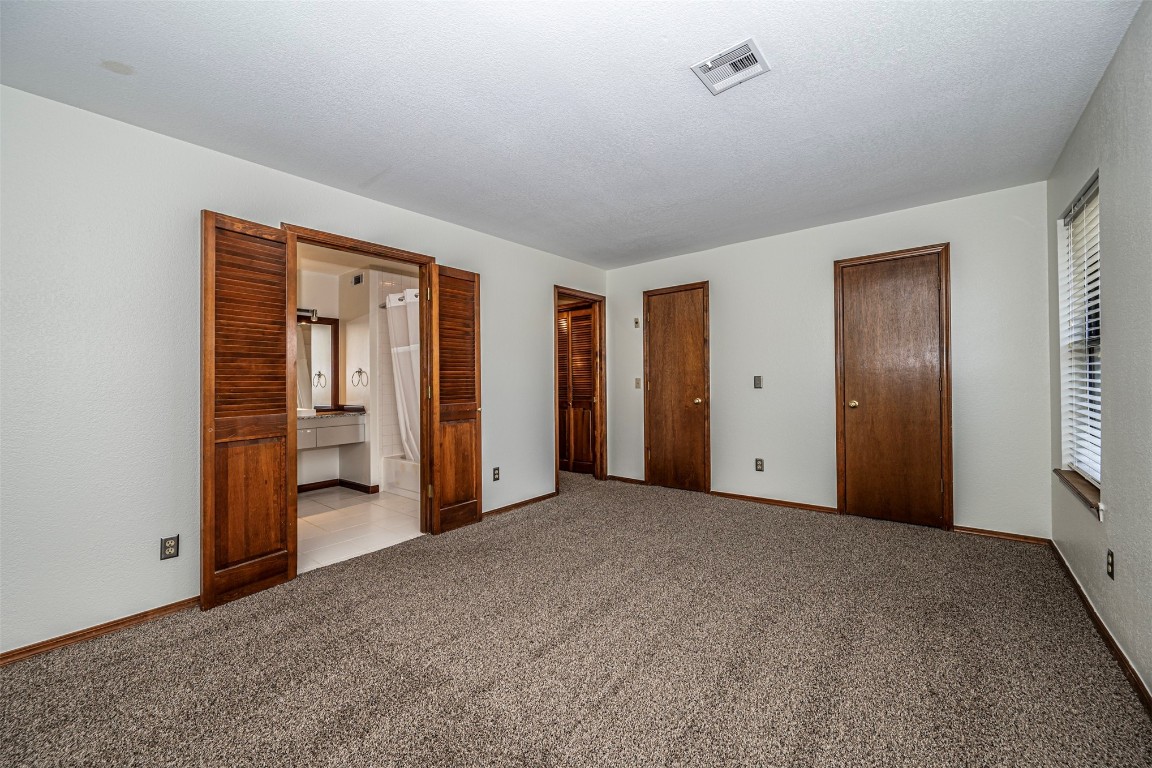4400 Hemingway Drive, #242, Oklahoma City, OK 73118 unfurnished bedroom with light colored carpet, a textured ceiling, and ensuite bathroom