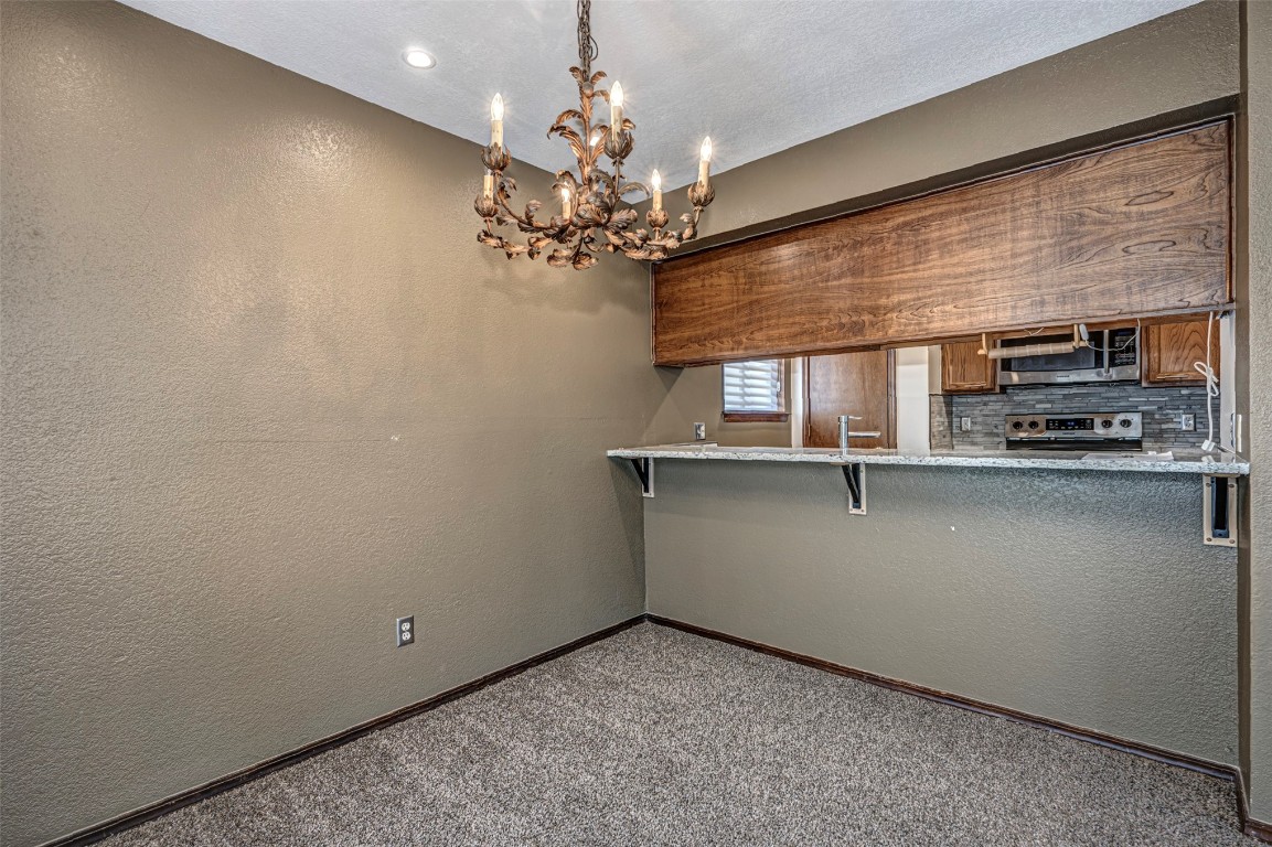 4400 Hemingway Drive, #242, Oklahoma City, OK 73118 kitchen with backsplash, range, carpet, and a kitchen bar