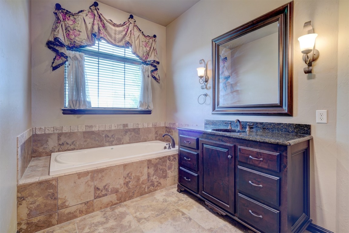 2833 Silvercliffe Drive, Edmond, OK 73012 bathroom featuring tiled tub, vanity, and tile floors