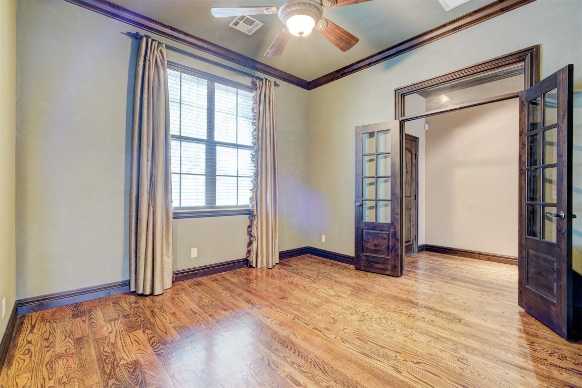 2833 Silvercliffe Drive, Edmond, OK 73012 unfurnished bedroom featuring ceiling fan, light hardwood / wood-style flooring, and crown molding