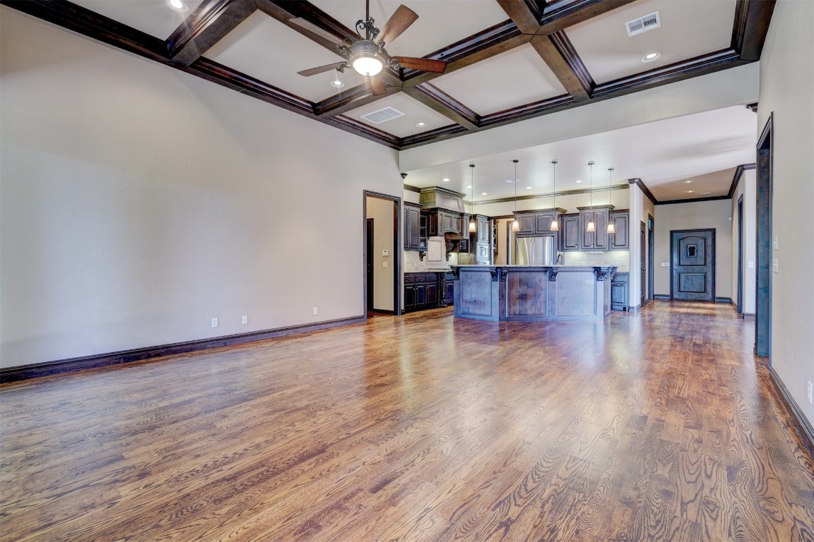 2833 Silvercliffe Drive, Edmond, OK 73012 unfurnished living room with light hardwood / wood-style floors, beamed ceiling, a high ceiling, coffered ceiling, and ceiling fan