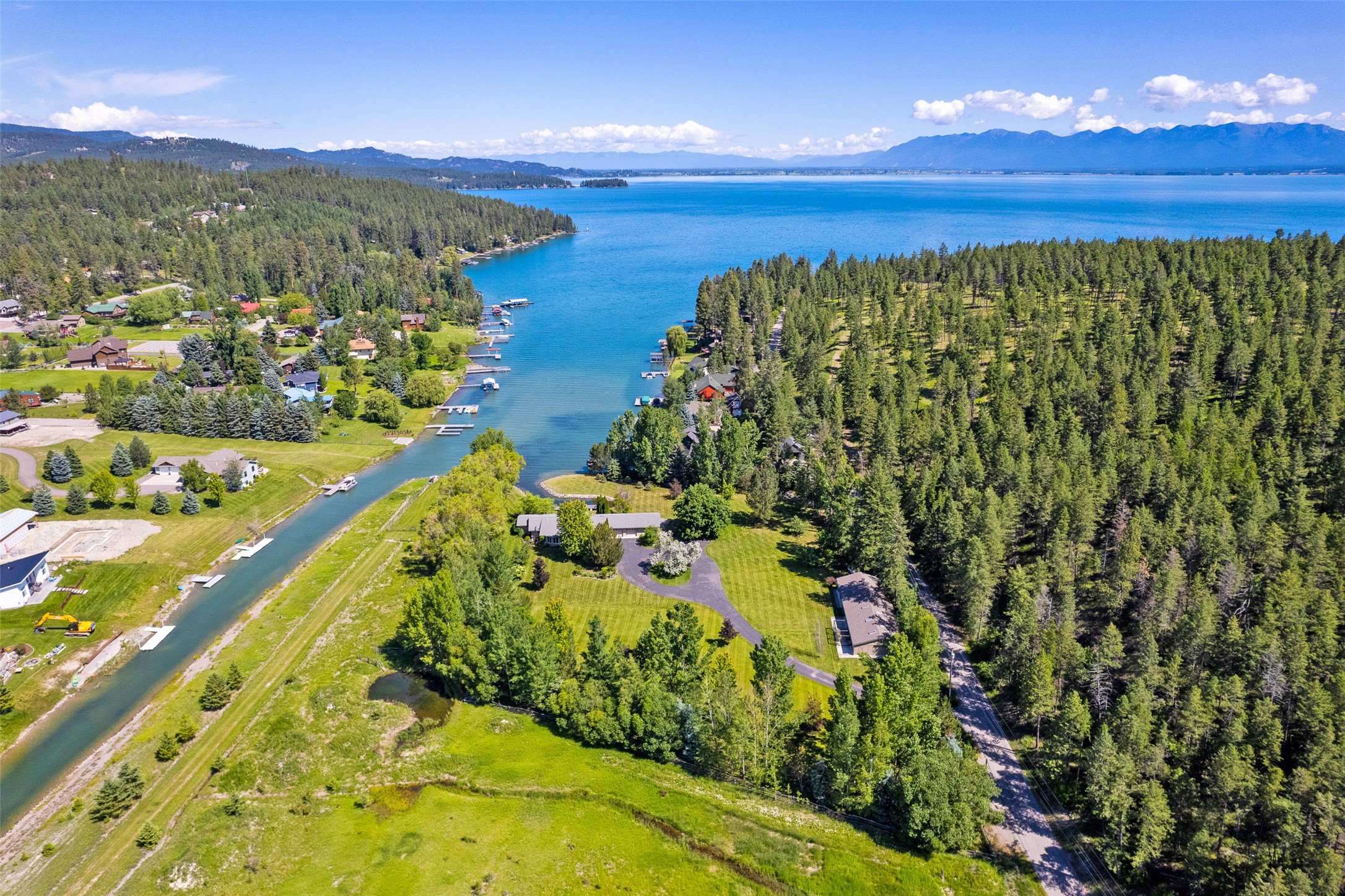 Embrace the tranquility of this rare 3.5+ acre waterfront property on Flathead Lake. Boasting 450+ feet of lake frontage in Peaceful Bay you will enjoy unparalleled views spanning from Caroline Point to Somers Bay and North Fork. The estate comprises a 2,683 sq.ft. main house, meticulously remodeled and expanded in 2009, featuring an open floor plan with remarkable views from every room. The kitchen is fitted with state-of-the-art appliances, Caesarstone quartz countertops, a UV water filter system and a walk-in pantry. The spacious living area, bathed in natural light, showcases a floor-to-ceiling stone propane fireplace and a 4-season sunroom with beautiful views of the yard and gardens. There are four bedrooms, including a master suite with a large walk-in closet, and a luxurious jetted tub in the master bath. Bathroom facilities are contemporary, featuring quartz and granite countertops and heated ceramic tile flooring. A versatile 1536 sq.ft. barn provides a workshop and office, complemented by a heated 2.5 car garage for all your storage needs. The guest house has a full kitchen and bath which also offers impressive lake views. Exterior features include an attached extra-long garage, 2 RV spots with hookups, 2 docks, and a private cove entrance. This one-of-a-kind estate epitomizes lakeside living at its finest, a sanctuary of peace and beauty that is both personal and timeless. Call Mark Kuhl (406) 407-7509 or your Real Estate Professional.