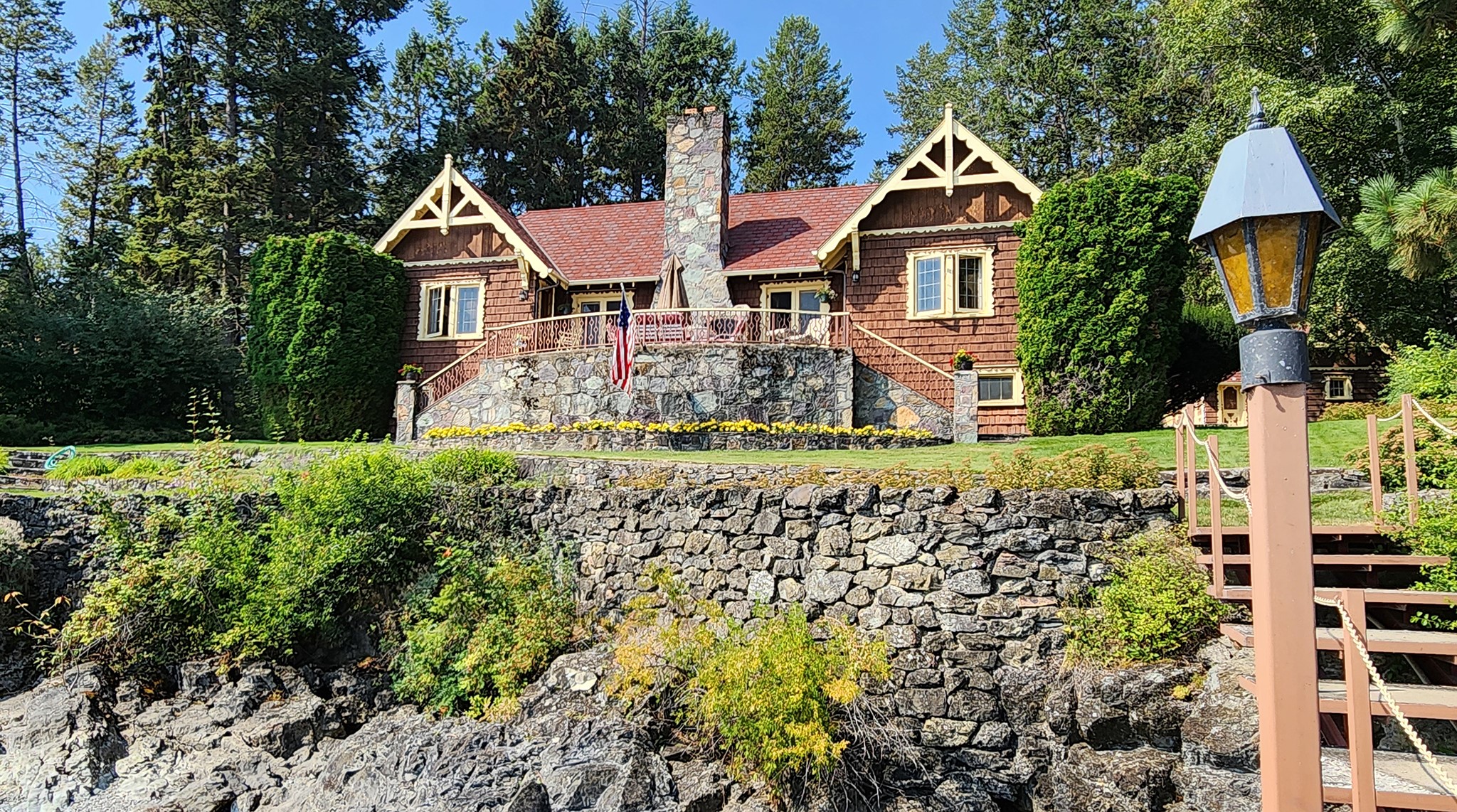 Since the 1940s, passing boaters have enjoyed this picturesque "Gingerbread" house along the westshore of Flathead Lake. This historic home sits on 3.7 forested acres with378 feet of frontage spread over multiple lots (see survey) on the tip of Caroline Point. The circular driveway is bordered by long standing rockwork , landscaped flower beds and lawns wrapping around the home down to the lake. Enter into a large Living Room with rock fireplace. As you discover the home, you'll notice all the carved woodwork detailing, wood floors, and historic lighting & textiles. The south wing has 2 Bedrooms and full Bath. The north wing has the Kitchen and Dining Room, third Bedroom with attached 3/4 Bath. Downstairs is a bedroom, storage and utility room. Mornings on the stone patio you will enjoy the eastern panorama of the Swan Mountains,Glacier Park and the sound Flathead Lake's clear water splaching on the rocks.Walk down the stone path to the the concrete dock with  covered boat slip for re- laxing in the sun, a swim or hop on your boat for a scenic cruise, fishing or watersports. Other buildings include the original double garage with work room and a laundry cabin. To the west of the home is the forested interior knoll of Caroline Point for a guest house or even a new main home leaving the lakefront home for guests or day use.   Call Scott Hollinger at 406-253-7268 or your real estate professional.