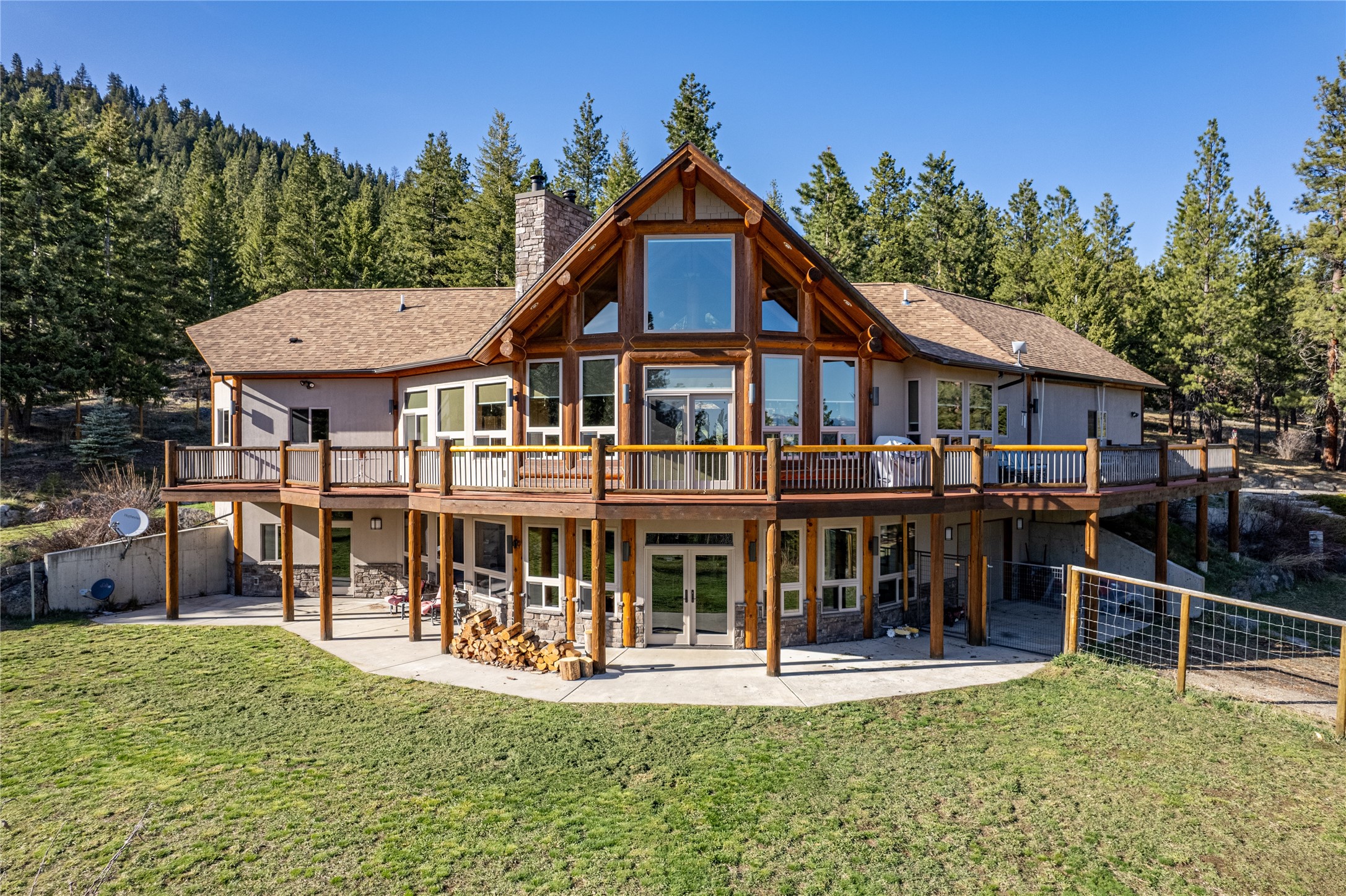 Nestled among the pines, on a sprawling 116± acres, this custom-built post and beam home in Victor offers a unique blend of rustic charm and refined elegance. Equipped with one of the best producing wells in the valley and situated against the stunning backdrop of the Bitterroot Mountains, this property epitomizes tranquility and seclusion. Surrounded by Forest Service land to the north and west, and conservation easement land to the south, this home ensures uninterrupted panoramic views of its breathtaking natural surroundings. Boasting 3,270 Sq. Ft. of living space, the residence features meticulous craftsmanship with intricate wood detailing, king log trusses, and a harmonious fusion of ceramic and wood flooring that maximizes in-floor radiant heating. Step through the geometrically designed entrance into the main level, where vaulted cathedral ceilings and expansive windows invite abundant natural light and passive solar heating while showcasing vistas of the Bitterroot Valley. The main floor's centerpiece is a magnificent sandstone Tulikivi fireplace, creating a cozy ambiance in the living and main floor bedroom. The chef's kitchen is a culinary delight, outfitted with cherry wood cabinets, forest green Silestone countertops, an island with an eating bar, and a generous sized pantry. The primary suite, conveniently located on the main level, offers a lavish retreat with a spa-like bathroom featuring a custom-tiled shower, dual vanities, and spacious walk-in closets. The walkout lower level extends the living space with a sizable living room, an additional bedroom, and a third non-conforming bedroom, or den, complemented by a convenient kitchenette for guests' comfort. complemented by a convenient kitchenette for guests' comfort. Outside the main floor is a sprawling deck with an awning that provides an idyllic setting for outdoor entertaining while soaking in the breathtaking views. The property also features 2 small ponds and apple, pear and cherry trees. Recent updates include a freshly painted exterior stucco, newly sealed posts and beams, and a new roof, ensuring the home's impeccable condition. Complete with a comprehensive fire suppression system with a 400 gallon cistern, this property seamlessly integrates rustic elegance with modern amenities and security, offering an unparalleled retreat in the heart of the Montana wilderness.