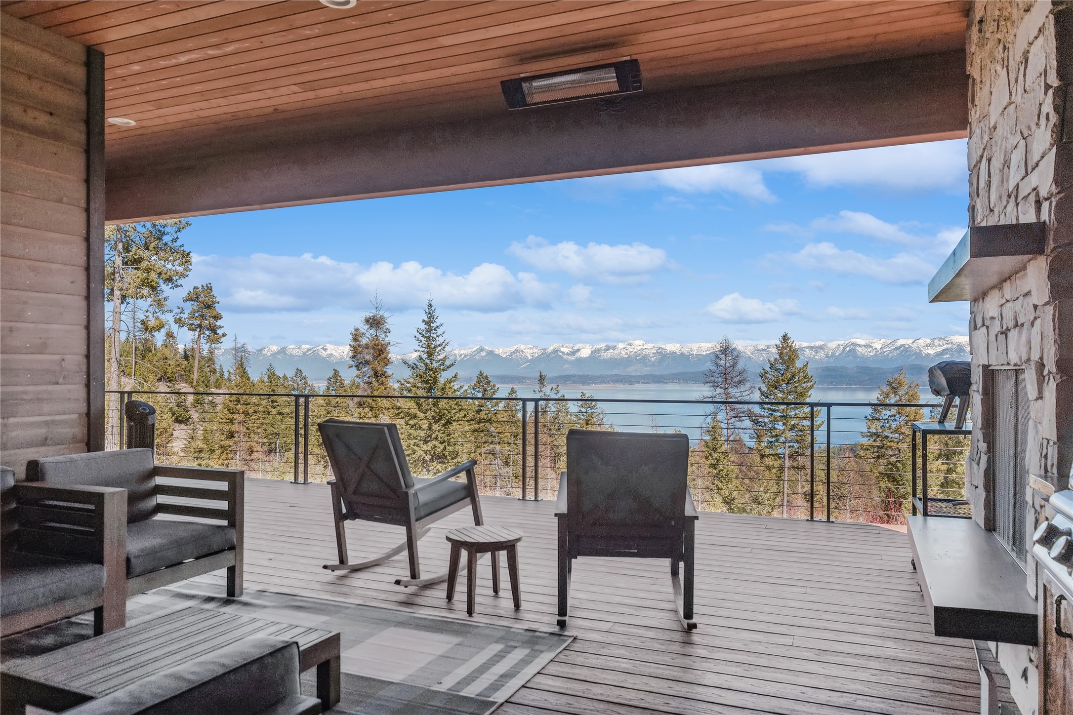 You will be impressed by the stunning lake and mountain views from this impeccable Lakeside residence. Built in 2020, this 4152 square foot home features a primary suite with walk-in closet,  a guest suite and office  on the main level, with 2 additional bedrooms, living area, full bath, and game room on the lower level.  The efficient kitchen features  quartz countertops, modern fixtures, soft close drawers, and plenty of storage.  The living room has open flow with engineered hardwood flooring , stone fireplace, and adjacent dining area. One of the features that sets this home apart from the rest is the living room/dining room wall of windows that folds all the way open for expanded indoor/outdoor living and entertaining in the spring, summer, and fall.  Enjoy unobstructed views of the mountains and Flathead Lake while sipping a cup of coffee, celebrating with a neighborhood cookout, or relaxing with a glass of wine at sunset on the deck. The attached 3-car garage keeps your cars protected and safe. The view of the mountains and lake are among the many highlights of this property. This home is designed to flow seamlessly between all living areas. There is plenty of space indoors and out to enjoy the views, take in nature, and admire the starlit sky.