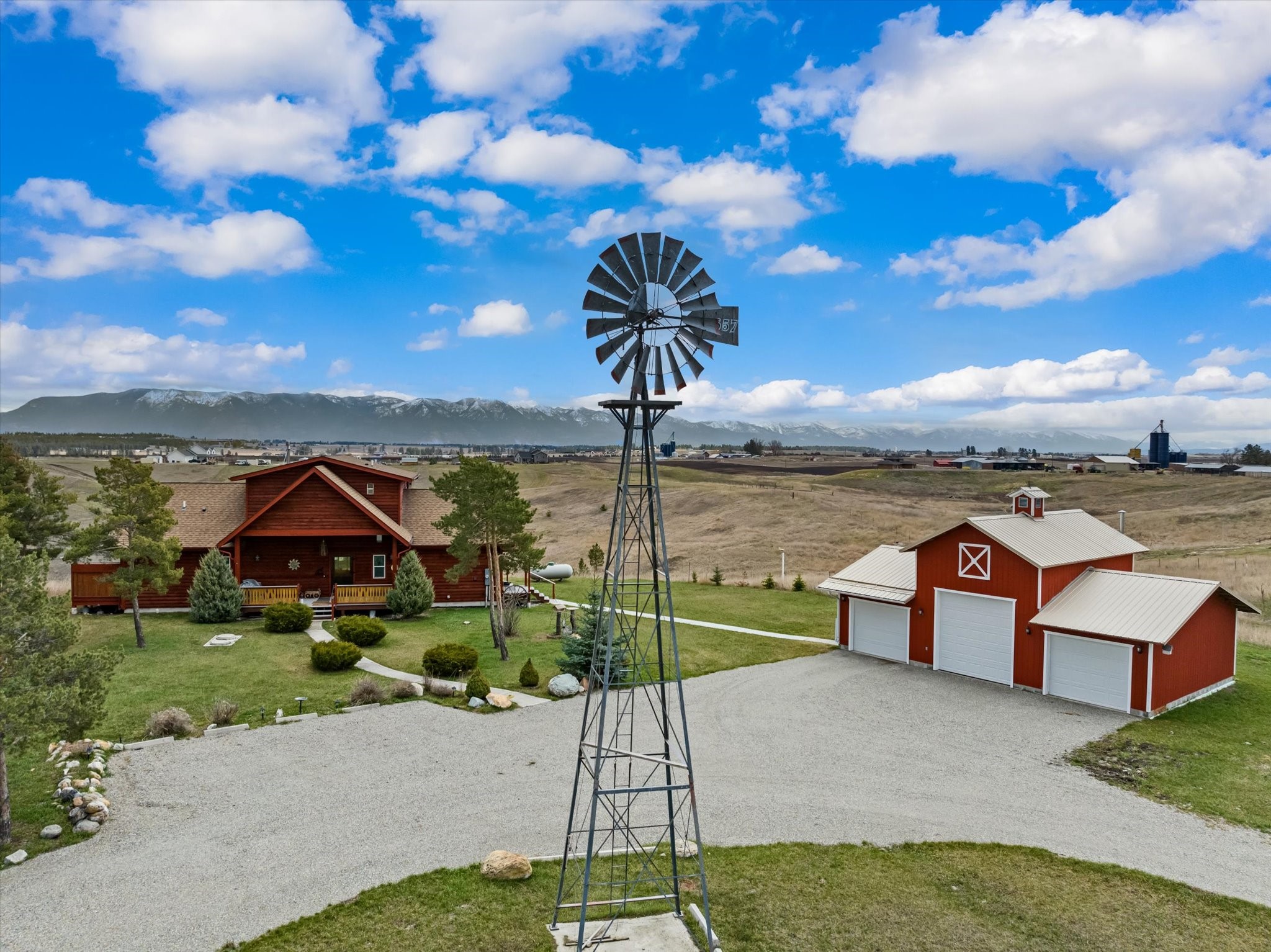 PRICE IMPROVEMENT! There’s nothing like driving down a country road, being greeted by a nostalgic windmill and a classic red barn as you approach your new home. Welcome to 657 Lone Coyote Trail in Kalispell, Montana.  Nestled on a sprawling 7.7-acres with unparalleled views of Whitefish Mountain Resort, Glacier National Park, and the majestic Rocky Mountain Range. Featuring a 3 stall garage and large shed with a lean-to that provide ample space for storage or the ability to create your own mini farm. This charming split-log home boasts 3025 square feet, 2 bedrooms and 4 bathroom, an inviting open-concept living space is complete with tongue and groove ceilings, floor to ceiling east facing windows and a fireplace that creates a warm atmosphere perfect for gatherings and relaxation. Step into the spacious kitchen equipped with a full size double oven, inset lighting, granite countertops, hickory cabinetry with soft-close features and a large pantry. The main level primary bedroom boasts an en suite with tile surround and dual sinks; a walk-in closet and access to a covered addition ideal for a serene spa or a personalized sanctuary. Ascend the stairs to discover a versatile bonus area overlooking the living room via an indoor balcony; a perfect place to admire the mountain vistas. A second bedroom and a full bathroom complete the upper level, providing ample space for guests or family members. The walk-out basement presents additional living space, ideal for use as a bonus living area or entertainment zone, along with a 3/4 bathroom and ample storage opportunities. This property strikes a perfect balance between country living and convenience with easy access to amenities including Costco, Logan Health Hospital, and plenty of shopping opportunities just a few miles away. If you're ready to experience Montana living at its best don't hesitate to schedule an exclusive showing. Call Holly Naldrett 406-407-2355 or your real estate professional.