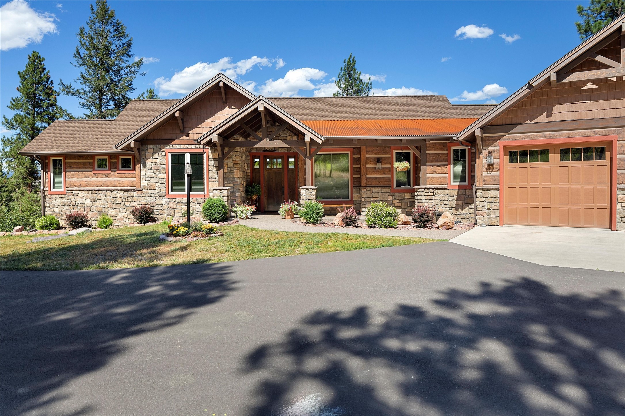 Located on the Big Flat on the west side of Missoula's valley, this property sits on 5 acres of forested land with stunning views of the Clark Fork River and breathtaking sunrises. Built by Edgell Building in 2015, the home features Everlog concrete log siding creating a blend of rustic and modern style.
Outside, enjoy the fire pit patio surrounded by stone walls and landscaping, perfect for gathering under the Montana sky. The screened porch offers a cozy spot for coffee or cocktails and the spacious deck allows for al fresco dining while taking in river views and wildlife including resident bald eagles.
Inside, the main floor boasts a spacious living room with timber framed ceilings and a rock fireplace, flowing into the kitchen and dining area. The primary suite with a walk-in closet and on-suite bathroom, a second bedroom/office, full bath, half bath and laundry facilities complete the main level. The daylight walkout basement provides ample space for entertaining, with two bedrooms, a full bath, and a family room featuring a wet bar.  The home is equipped for comfort year-round, with a geothermal heat pump, gas fireplace, central air conditioning, and a heated triple car garage.
With its picturesque setting and quality craftsmanship, this property offers the epitome of Montana living—a peaceful retreat to create lasting memories with loved ones.

Contact Carroll Anne Sowerby at 406-544-9537 or your real estate professional.