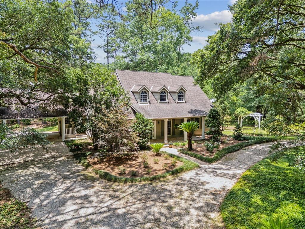 Enjoy the drive up the private road of this beautiful Acadian home nestled away in 16.5 park like acres of short leaf and loblolly pine, live oaks, and decades-cultured gardens of Southern Indica and Native azaleas, camellias, as well as gardenias. Listen to the wind in the trees, the drum of the pileated woodpecker, the calls of turkey and other wild birds, and the cacophony of the frogs and toads nestled in the woodlands below. And smell the freshness of the air as it drifts up the gently rolling terrain. The house overlooks a stocked 18 acre crystal clear lake with approximately 250 feet of lake frontage edged with pond cypress and native ferns. The lake is home to bass, bream, mallards, wood ducks, wading birds, and even bald eagles.

The house boasts an open floor plan that seamlessly integrates living dining and kitchen areas. Solid surface countertops, stainless steel appliances, and custom maple cabinets adorn the kitchen, while a gas fireplace warms the inviting living room that features 12 foot ceilings, hardwood floors and built in cabinets. With three generously sized bedrooms and two baths, each room has an inviting view of the property. The primary suite includes a large custom walk in closet, and ensuite bath and is steps away from the large covered back porch.  The property includes a 22'x12' shed with an open storage area, a 16' x 25' hand made louvered-wall pole barn with 25x8' lean to. Tankless water heaters, high efficiency Trane HVAC and heater, Canadian cedar exterior planking, 40yr roof Timberline Ultra shingles.

This property is secluded away from civilization, yet conveniently located 15 minutes from downtown Covington. Whether  you are looking for a retreat from the city, or always wanted to live in a house that is in the country, this property offers the perfect blend of peace, privacy, and natural beauty. What a rare opportunity.