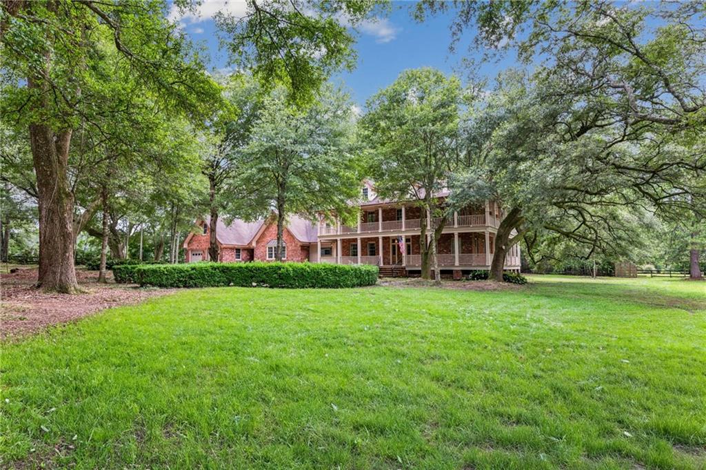 Seize this incredible opportuity to transform a magnificent 5 acre Southern plantation estate into your dream home. Envision your luxurious touches on this expansive canvas graced by sprawling oaks, mature trees and landscaping, all overlooking a large pond . The grand interiors, with soaring ceilings, wood floors and a majestic 4-sided fireplace invite your creative vision to shine in the expansive family room with cathedral ceilings. Imagine waking up in the spacious bedrooms that open to a charming veranda, offering tranquil views of the serene pond. With a workshop, a spacious 4-car garage, and a framed out wing ready for a 2 bedroom conversion, this property has endless potential. Embrace the chance to make this estate your own masterpiece!