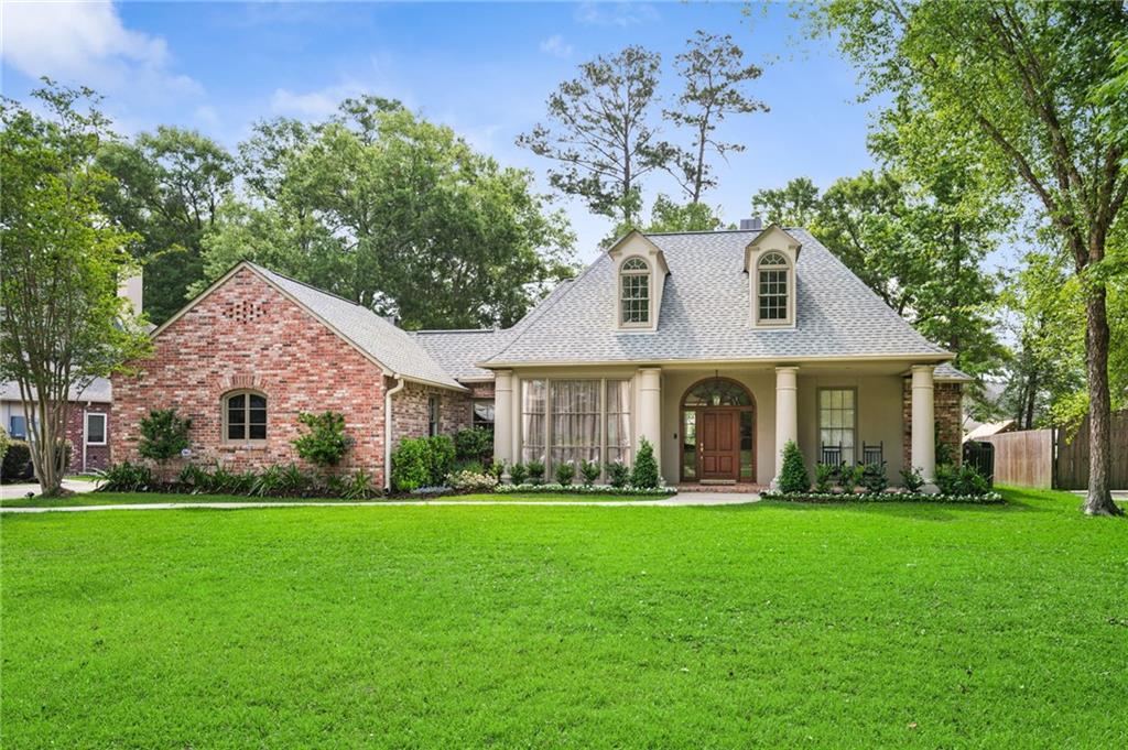 Stunning Andy McDonald Acadian Home Flood Zone C , Blue Ribbon MANDEVILLE schools located in a desirable private neighborhood offering a  clubhouse, pool, and tennis courts. Beautifully landscaped lot with lush gardens and brand-new privacy fence. This 5-bedroom 4 bath home with an open floorplan is an Entertainer’s Dream! Gorgeous grand cypress front door and open floor plan where the beautiful back yard is brought inside through floor to ceiling windows.  10-foot ceilings throughout the first floor.  Enjoy three separate living areas with seamless flow from the formal dining room, great room, kitchen with adjoining hearth room and the upstairs has another living / playroom. Three bedrooms, including a private primary suite and guest/mother-in-law suite, each with full baths, are located on the first floor. The large primary suite has his and hers walk in closets and is heated/cooled by a dedicated HVAC unit to ensure ultimate comfort. Upstairs features two additional bedrooms with walk in closets and a Jack-and-Jill bathroom with 2 separate toilet and sink areas. The open entertainer’s kitchen and butler’s pantry has custom cypress cabinetry, granite countertops, large island, walk in pantry, high-end Thermador appliances including 5 burner gas stove with retractable downdraft vent, and a large-capacity ice maker in butler’s pantry.  Other amenities include: 10’ solid oak flooring, 2 fireplaces, 3 HVAC units, large laundry room, 2 car garage, 3 decked attics, in ceiling speakers.  Recent updates include fresh paint throughout, updated LED lighting, updated bathrooms, new 30 yr architectural roof in 2019, new custom spanish cedar dormer windows, replaced 13 insulated windows in 2025(with 5 yr warranty), and more.  This exceptional home is move-in ready! Schedule your showing today to discover this perfect blend of Southern charm and modern comfort in this timeless and elegant home.