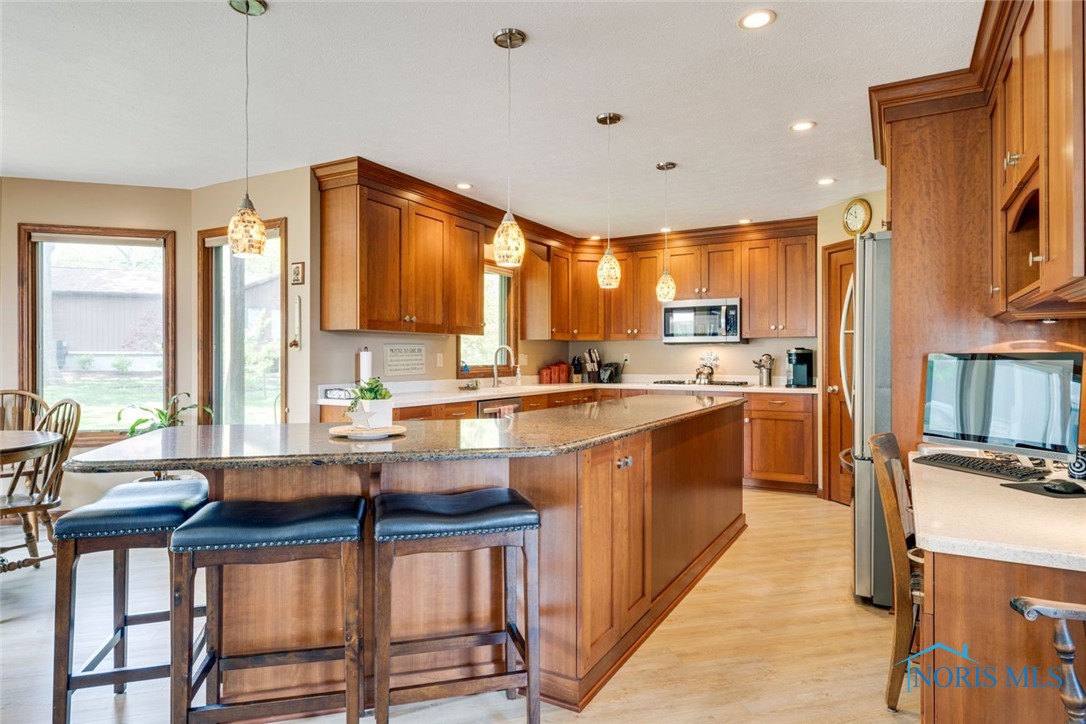 Upgraded kitchen with large island, built in desk area, pantry and custom cabinetry