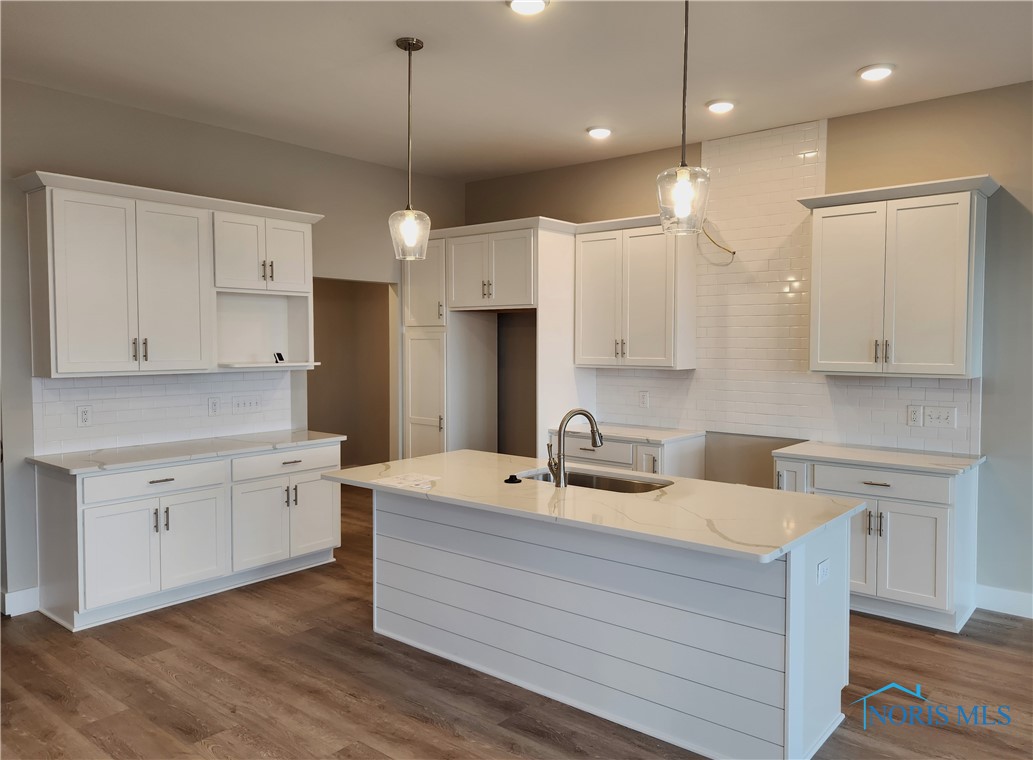 The elegant kitchen has Shaker-style soft-close cabinets with quartz countertops and a subway tile backsplash.