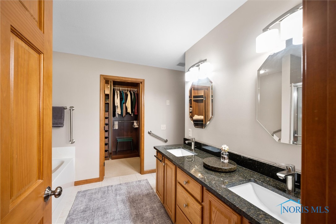 Primary bathroom with granite countertops on double bowl vanity, tile floor, jetted tub and step-in shower
