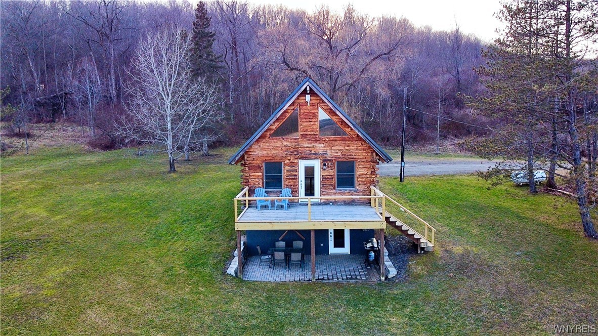 Discover this charming 2-bed, 1.5-bath log home (currently an Air BnB), a versatile retreat suitable for getaways, or even year-round living. With its inviting open floor plan, cathedral ceilings, expansive windows, the unique charm of this home features a loft that gracefully overlooks the living space below. The fully finished basement offers a spacious layout w/a laundry room, comfortable living space & a half bath. The walk-out access provides a connection to the outdoors, allowing you to embrace in solitude or gather w/friends & family around the firepit.  An ideal & tranquil setting, with stunning panoramic views of the surrounding natural beauty. Experience a seamless blend of architectural elements that not only create spaciousness but also integrate the captivating outdoors, resulting in a living space that harmonizes perfectly with its picturesque surroundings.  A short drive to Ellicottville & the renowned Holiday Valley Ski Resort. Fully furnished - mirror, foosball table & the agriculture not included.