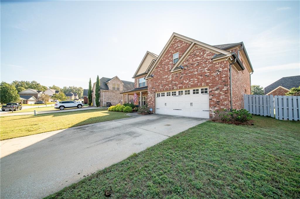 Two-story brick home with a white double garage door and broad concrete driveway.