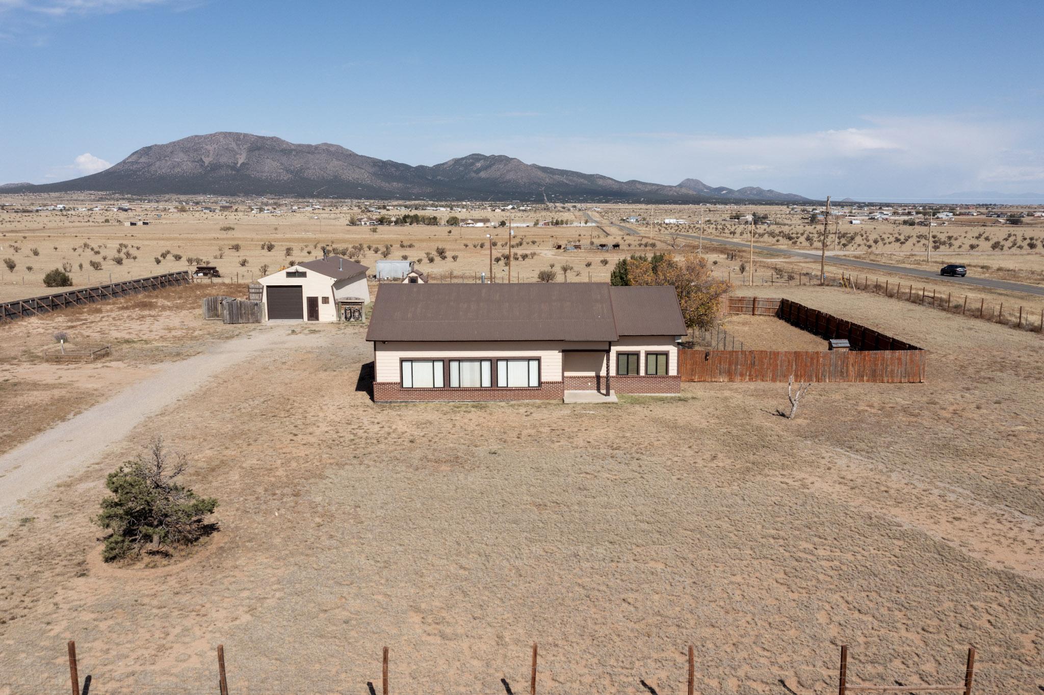 Impeccably maintained custom home in the heart of Edgewood, NM! This split-level home has had many incredible updates in recent years, including a full kitchen remodel, bathrooms, flooring, paint, you name it! New furnace and ductwork in place.  The pellet stove is on a thermostat and provides warmth throughout the entire home. Metal double pane windows. High ceilings in the living room and the loft, with tons of natural light which creates a warm and inviting space. The loft offers the potential to turn this home into a 3 bedroom. Sitting on over 2 full fenced acres with beautiful views of South Mountain, there are multiple outbuildings, including a nearly 1,000-square-foot workshop with an additional 300 feet of loft space, complete with multiple heat sources. Community water and natura
