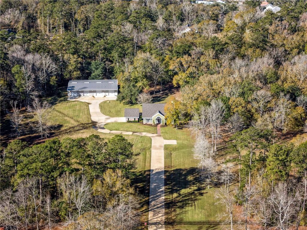 Embrace peaceful seclusion on this 20 acre Mandeville estate with a 6000 square foot workshop! Open floor plan with a 2 car attached garage, and scenic, extended driveway, this home defines versatility. The industrial-grade workshop,  features 4 installed entry bays with motorized doors, a distinct car workspace station with office, and an abundance of storage potential for even the heaviest equipment! The sprawling trees covering the grounds add to the tranquil atmosphere. The radiant natural lighting in the foyer and formal dining room provides a gentle greeting. Enter into the living room, encapsulated by 20+ foot vaulted ceilings. Wrap around into the spacious kitchen and breakfast area, all surrounding the welcoming central staircase. The primary suite leads into the en suite bath, which flows seamlessly into the sunroom with sauna. Upstairs, spacious bedrooms await. Roof replaced in 2022. Experience the entire scope of this wonderfully kept, private Mandeville estate today!
