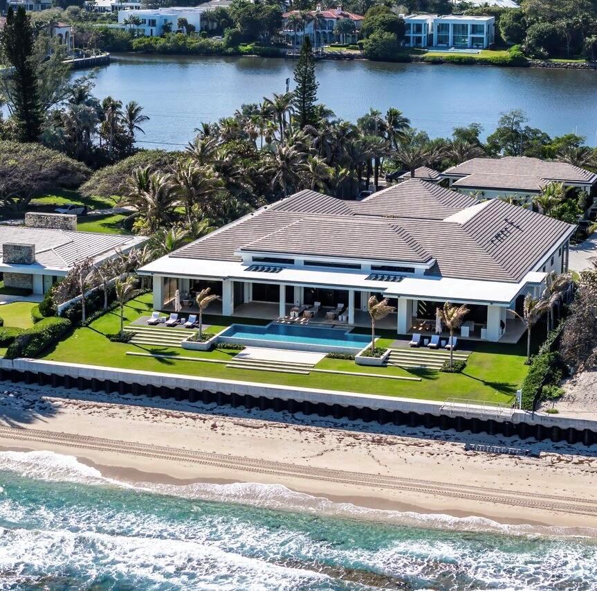 Set between the Atlantic Ocean and Intracoastal Waterway, 1160 S. Ocean Blvd is a rare retreat where architecture and nature exist in perfect harmony. Spanning 27,745+/- square feet under roof on nearly 2 acres, this newly completed estate offers 160 feet of direct ocean frontage and private Intracoastal access, creating an unrivaled connection to land and sea. Designed with balance and thoughtful craftsmanship, the 25,197+/- square-foot main house flows effortlessly from one space to the next. From the grand entry hall, the journey unfolds--a symphony of light and space, where the living room merges with the ocean beyond. The formal dining room, with its ocean-facing bar, sets the stage for elegant entertaining, while the open-concept kitchen and family area form the heart of the home. A private catering kitchen allows staff to work discreetly behind the scenes. The primary suite, occupying its own wing, features a private sitting room, ocean-view office, and dual dressing rooms. The spa-like primary bath, wrapped in Calacatta marble, offers a stone soaking tub and dual water closets. Three additional guest suites on the main level each provide private en-suite baths and walk-in closets. On the lower level, the home transforms into a haven of leisure and wellness, featuring a state-of-the-art gym, steam shower, wine room, game room, and immersive theater. Two additional bedrooms offer private accommodations for staff or extended family. From concept to completion, this home was orchestrated by female builder Siobhan Zerilla, principal of Bluedoor Building, bringing vision and artistry to every detail. For the automotive enthusiast, a climate-controlled 13-car garage provides the perfect space for a prized collection. A separate guest house offers two bedrooms, two full baths, a half bath, a full kitchen, dining area, and private laundry, while its own cabana and private pool create a secluded retreat. The outdoor spaces are equally intentional, with a covered courtyard and east-facing loggia, designed for meditation, relaxation, and celebration. A private dock, equipped with two boat lifts, allows effortless Intracoastal access for yacht owners and water enthusiasts. Every surface, every detail has been curated for those who expect the best. White oak wood floors add warmth, complemented by Santorini Shell Stone, which transitions from indoor elegance to outdoor serenity. The home's refined palette is completed with Calacatta Gold, Black Alexander Honed stone, bespoke plaster walls, mahogany, and white oak accents. This is more than a home&#x14;it is a journey, a sanctuary where every detail whispers serenity. 1160 S. Ocean Blvd, Manalapan&#x14;where life finds its rhythm.