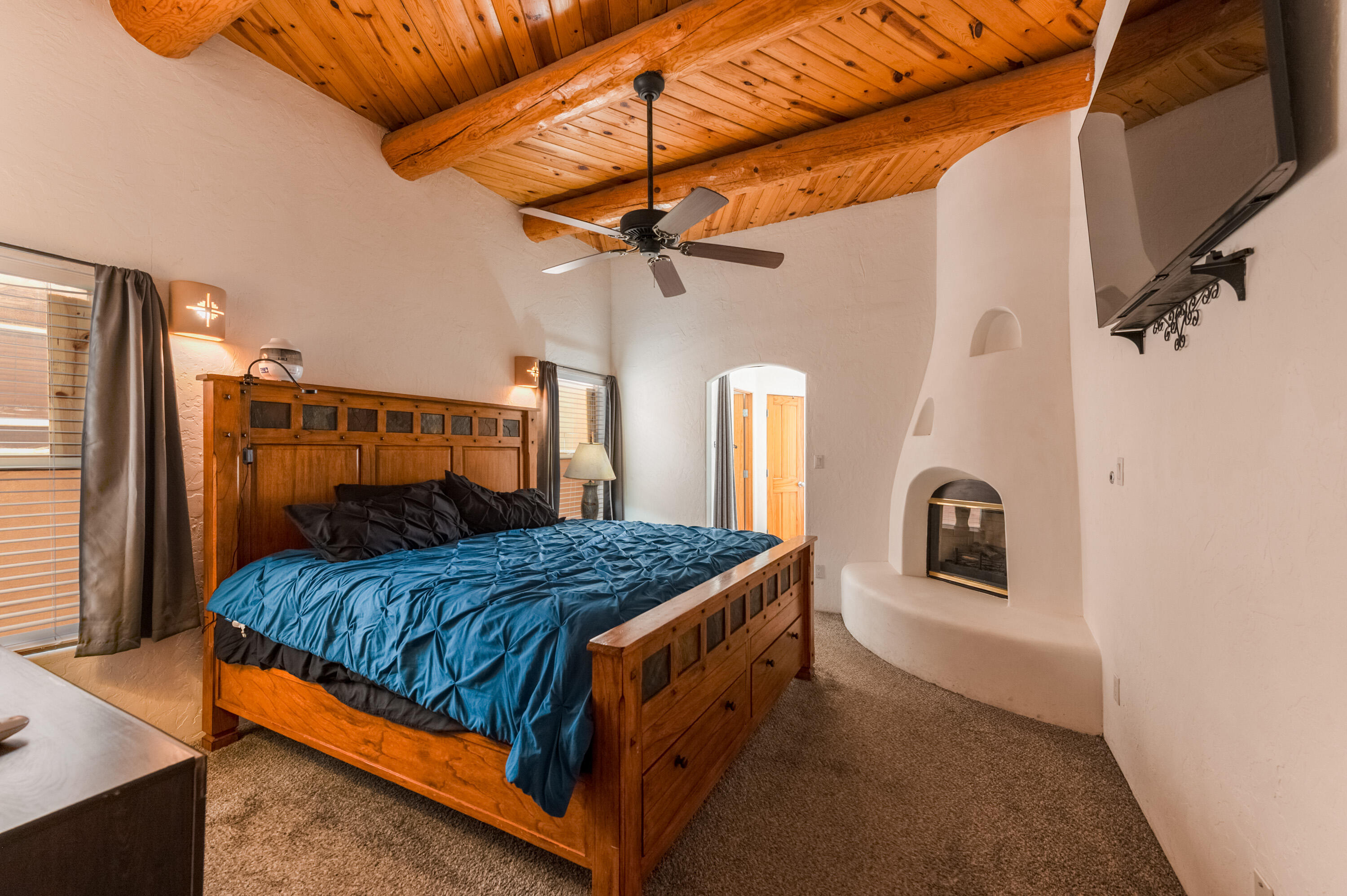 Located in a gated community.   You can really live New Mexico in this home with so many charming Southwest features including a courtyard entry, carved posts, viga ceilings, and 2 kiva fireplaces!   Cozy Living room with raised ceiling, tongue and groove wood ceiling and, vigas, kiva FP and patio door to rear yard.   Pleasant kitchen great U configuration for cooking, gas stove and breakfast bar as well as a rounded wall of windows in dining area,  Fall asleep in peaceful primary bedroom with kiva frplc.  Generous bath with soaking tub, sep shower and double sinks.  2 additional bdrms on opposite of home with a bath in between.  Attached 2 car garage.   Rear patio has a fireplace too. Refreshed stucco and refreshed roof.