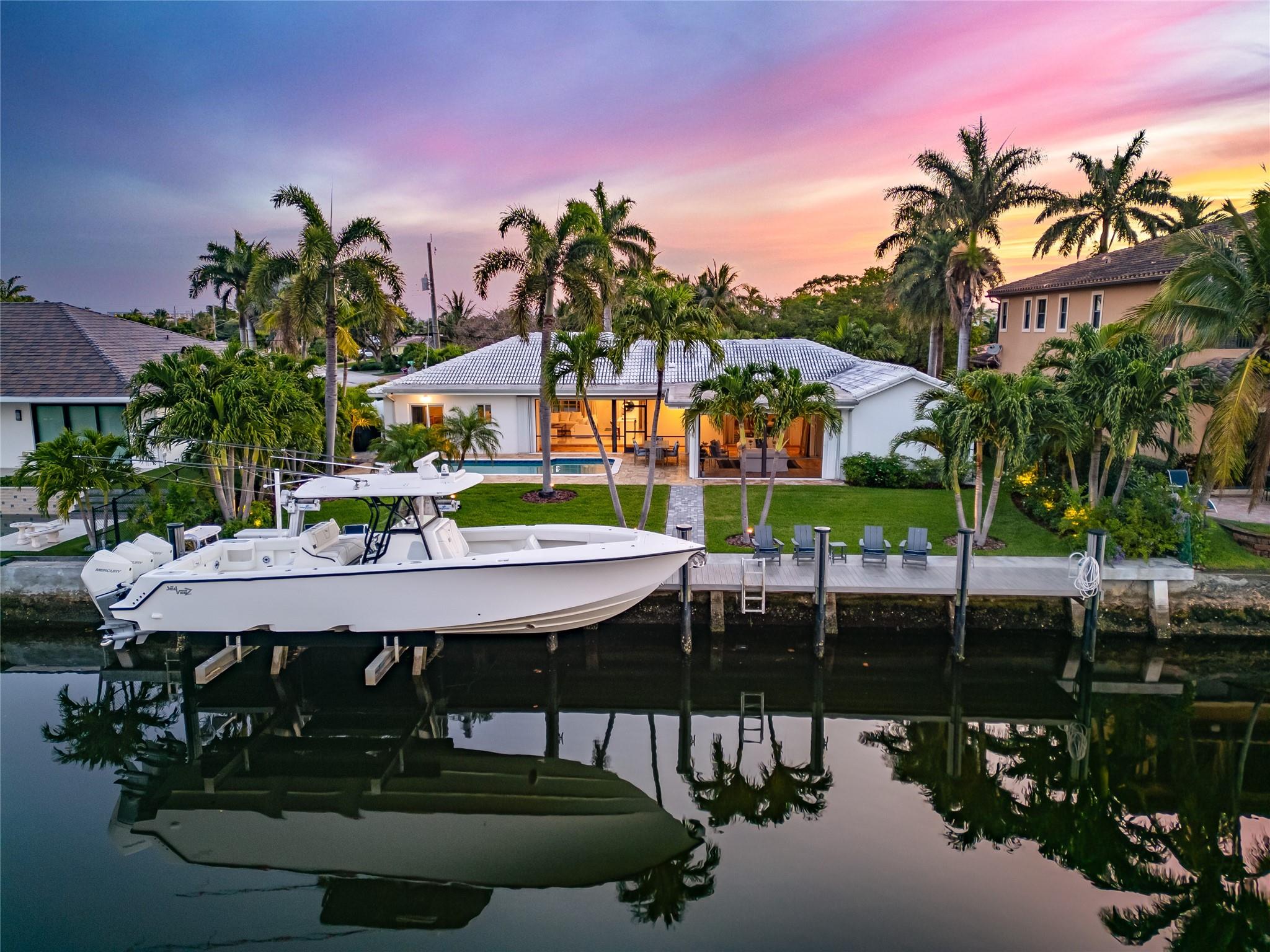Introducing The Commodore’s Boathouse in the desirable Cove enclave of East Deerfield Beach, sited on 90’ of deepwater frontage with picturesque southern long water views at an intersecting turning basin on the extra wide Kingfisher Waterway. This fully furnished exceptional estate offers 3 bedrooms and 3 full bathrooms with 3,001+/- square feet of total space. Outdoor entertainment is enjoyed under the expansive screened-in porch. Amenities include a resort-style heated & chilled pool, updated interiors, impact windows/doors, and more. Ideal for the avid boater, there is a 70' full-service composite yacht dock with 20,000± lbs boat lift just minutes to both the Boca & Hillsboro Inlets. Conveniently located within a short distance to Deerfield Beach Pier & nearby world-class restaurants. 1410 SE 12th Street, East Deerfield Beach, Florida:  Just south of Boca Raton on South Florida’s Gold Coast, the desirable Cove enclave is conveniently located in east Deerfield Beach, known for its magnificent ocean beaches, which have received the Blue Wave award, a designation given only to the most pristine beaches in Florida. The city’s picturesque 920-foot-long fishing pier is a local landmark, and excellent boating and fishing waters add to the area’s appeal as a water-sports paradise, with many beautiful waterfront estates on the Intracoastal Waterway and ocean-access canals. The Cove also offers easy access to I-95, the Sawgrass Expressway, placing The Boca Raton Resort, Royal Palm Yacht and Country Club, Mizner Park, and the Boca Town Center a few miles away.

PROPERTY: 
 
Visually striking, an updated paved horseshoe driveway circles around an oasis with palms creating a dramatic approach, while residents enjoy year-round outdoor entertainment under the expansive screened-in outdoor living  and dining lanai that flows out to the resort-style heated and chilled pool set within a travertine-paved patio. Offering 90± feet of deepwater frontage and a 70-foot full-service composite yacht dock with a high speed 20,000-pound elevator boat lift, boating enthusiasts appreciate easy access to the Intracoastal Waterway and both the Boca and Hillsboro Inlets with no fixed bridges.

RESIDENCE: 

Welcome to ‘The Commodore’s Boat House,’ evoking a nautical and luxurious ambience that especially appeals to boating enthusiasts and those seeking waterfront living in desirable East Deerfield Beach’s Cove enclave. With picturesque, southern, long-water views at an intersecting turning basin on the extra wide Kingfisher Waterway, this exceptional estate offers three bedrooms and three full bathrooms with 3,083± total square feet, where a mid-century-meets-modern aesthetic augments updated interiors that include the kitchen and bathrooms, fresh paint, and porcelain-tile flooring throughout. The astutely designed layout  places the living room and family room, as well as the one of the primary suites, opening through pocketing sliding glass doors to a wraparound screened lanai, overlooking the pool, patio and serene water views. With a circular flow, the  family room joins the all-white-and-stainless kitchen via a cook island that accommodates pull-up seating, and just adjacent, the dining room fluidly transitions into the living room. The secondary primary suite offers views of the front gardens, while the water-view guest bedroom comprises an ensuite bathroom that can also serve as a cabana bath. Additional amenities include impact windows and doors that open the entire residence up for ocean breezes and tropical living, ample closet and storage space, and a one-bay oversized garage.