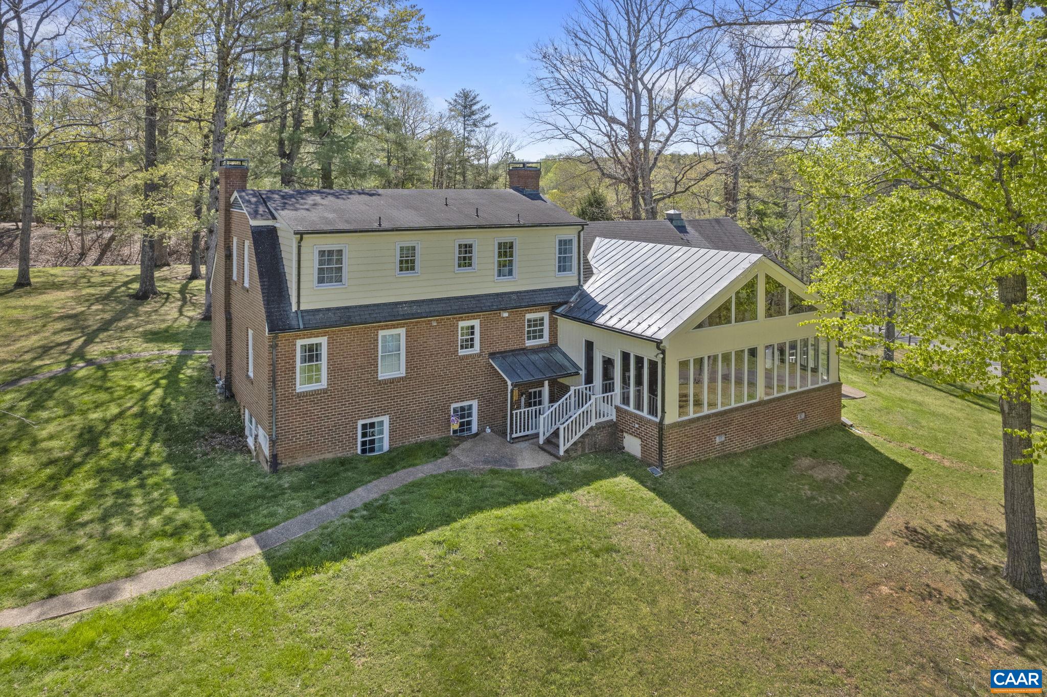 Paddleboard on the LAKE in your own backyard! Nearly 12 acres of lakefront property and a stately 5 bedroom, 3.5 bath home with terrace level apartment situated in the centrally located Carrsbrook neighborhood RIGHT IN TOWN! Renovated, improved and tastefully updated, Fairgrove features a well appointed kitchen with tile backsplash, granite counters and a large island. Just steps away is the dining area with brick floor, fireplace and dramatic natural lighting. The lake-facing sunroom literally shines with three walls of glass, hardwood floors, vaulted ceilings and exposed beams. Included on the entry level, a gracious foyer which opens to traditional family and living rooms, a half bath, home office, mudroom and laundry as well as access to an attached garage. Upstairs are three additional bedrooms including the Primary bed and bath with fireplace as well as a full hall bath. The terrace level apartment features two additional bedrooms, a full kitchen and bath and generous living room with brick fireplace and has both an interior and private exterior entrance. Behind the home and accessed by a separate drive is an additional 3 bay garage and an open face barn and all of this perched above the woods and lake beyond.