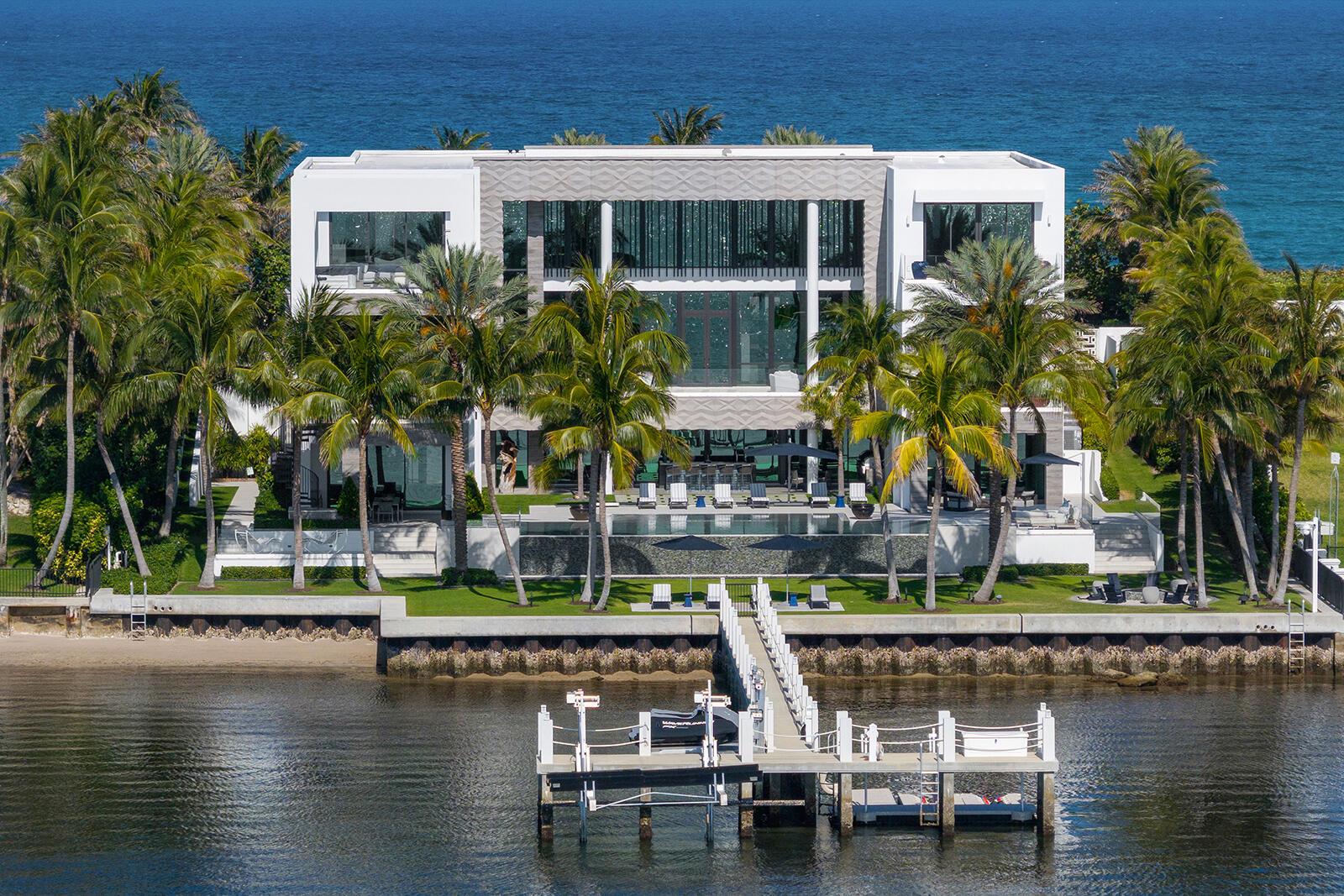 1940 South Ocean Blvd, Manalapan, FL 33462 - An Estate That Captures The Grandeur And Sophistication Of The World's Finest Luxury Hotel. Offered For The First Time, A Three Story 23K SqFt One-Of-A-Kind, Custom Built, Contemporary Seaside Masterpiece Stands Majestically Overlooking Nearly Two Acres Of The Florida Intracoastal Waterway And The Powdered Sand Shores Of Manalapan's Atlantic Ocean - Home To The Uber-Wealthy And Just South Of Americas Winter White House, ''Mar-A-Lago''. This Property Has Been Crafted From The Finest, Most Luxurious Resources, Fabrics, Stones And Natural Materials Available: Tunnel To Private Beachfront Cabana, Private Dock, Two Bowling Allies, Wellness Spa, Steam Room, Massage Room, Fitness Center, Movie Theater, Game Room, Craft Room, Elevator, Scullery Kitchen Personifying the spirit of relaxed elegance, this extraordinary gated, sun-drenched, three story, five bedroom, thirteen bath family home replete with underground tunnel to the 1,200 square foot beachside cabana with accompanying oversized lawns and Oceanfront balcony (the largest in Manalapan) stretches 150 feet across both the Ocean and Intracoastal Waterway, presenting nautical influences that suggest a breezy and serene palette - encompassing the essence of modern sophistication and coastal life. The underground tunnel offers a unique architectural feature, flawlessly connecting the main house to the lavishly appointed beachfront cabana. It ensures privacy and ease of access, making it convenient to enjoy the sun-drenched beach without stepping outside the boundaries of the estate. 

The Homeowners' natural flair for comfort was paramount when choosing each design element personally as the estates natural light and soothing aquatic tones of blues, grays, and sand invite a sense of peacefulness and balance, while blending the use of artisan hand-crafted tile work, marble, onyx, wood, metal, stone and glass along with the overhead glow from dramatic lighting fixtures in every room (each an individual work of art) add a heightened emotion of excitement. Each room boasts custom-built furniture that complements the architectural brilliance, creating a consistent yet vibrant visual narrative. The use of floor-to-ceiling windows throughout the home allows for an abundance of natural light to pour into every corner, creating a warm and inviting atmosphere. This thoughtful integration of natural light not only enhances the visible appeal but also contributes to the energy efficiency of the home. The interplay of light and shadow changes during the course of the day through custom fitted remote controlled black-out shades and sheer window treatments that follow the sun's path. The design elements of this home embrace a unique seaside escape, celebrating a way of life that treasures the beauty and tranquility of the coast - letting the soothing rhythms of the Ocean and the Intracoastal Waterway inspire you as you flawlessly and seamlessly move from room to capacious room without any interruption in style or mood.  

Upon entering this stately home through the grand oversized blue door, one floats like a dream past the open floor-plans formal dining room and luxuriously appointed living room and is immediately greeted by four 14-foot floor to ceiling limestone encased artistic wave design etched columns with accented lighting features there to remind you that the soothing Atlantic Oceans' surf is mere steps away. You can arrive in elegance to any of the homes three levels by either marble encased elevator boasting Intracoastal views through glass walls or a stylish cantilever wood staircase with marble and glass accents. To the south hall is a dramatic full-service backlit onyx bar flanked between twin rare and semi-precious lapis lazuli stone columns that create not only a striking focal point but also symbolizes a bridge between the earthly and the divine with elegance and artistry. A glass enclosed one thousand bottle temperature-controlled wine room and adjoining waterfront club room with its "11 Ravens" billiard table, bespoke design and meticulous craftsmanship makes this sophisticated space perfect for socializing and relaxation, inviting guests to unwind in elegant waters-view surroundings. Directly to the east one enters through glass encased sliding doors to the "Gentlemen's Office" displaying verdant views of the porte-cochere, front lawn and Ocean facing lounging area replete with glass fire-pit. Completing the middle / Ocean level, the gourmet kitchen with adjacent full service scullery kitchen equipped with state-of-the-art appliances and an abundance of custom commissioned sleek cabinetry seamlessly transition into multiple family and formal dining areas as well as the large west facing family room with outdoor covered loggia / grilling area using the Intracoastal Waterway as the  perfect scenic backdrop.

Spanning a sizable portion of the third floor, the oversized Homeowner's suite is a sanctuary of calmness, opulence and tranquility. This grand suite boasts breathtaking views of both the Atlantic Ocean and the Intracoastal Waterway. The suite features an expansive bedroom area adorned with luxurious custom furniture, including plush sofas, oversized chairs, cozy couches, marbled walls, wood floors and serving as the rooms' main focal point amidst all the lavish fabrics is a floor to ceiling custom crafted hide wall that carries onto the ceiling and down to a fireplace. The elegant design incorporates floor-to-ceiling windows that invite natural light to flood the space, creating a serene and inviting atmosphere. The individual his and her bathrooms within the suite are a masterpiece of design, exotic materials and comfort, equipped with a waterfront view freestanding sculpted soaking tub, multi-jetted showers, and expansive vanity areas adorned with jewel quality finishes. The use of high-end materials such as marble, onyx, and artisanal woodwork elevates the space, providing a moody spa-like experience. Adjacent to the bathrooms are three extremely generous sized, boutique-quality walk-in closets featuring custom-built cabinetry that provide ample space for a vast wardrobe. The suite also includes a private Oceanfront sitting room, perfect for relaxation. Flanking the east and west positions of the primary suite, sliding glass doors seamlessly flow onto the twin "Homeowners' Access Only" outdoor spaces where balconies, outdoor showers, and private hot tub await, perfect for enjoying picturesque Florida sunrises or sunsets. Continuing down the hall, the three additional guest bedrooms are adorned with en-suite bathrooms, plush bedding, custom-built furnishings, exotic stone counters, tiled or fabric walls, and expansive windows and balconies in each room that frame stunning views of either the Ocean or Intracoastal Waterway as well as the estate's lush surroundings. 

Upon entering the estate's entertainment and wellness lower level, immediately your senses are heightened by the unparalleled luxury, entertainment features and scenic Intracoastal views that surround you designed to elevate your living experience. The meticulously designed space boasts an array of amenities aimed at providing the utmost in relaxation and enjoyment. The lower level features a high-end Zen spa atmosphere complete with massage room, steam room, soothing multi-jetted showers with adjoining warm hued wood lockers providing a sanctuary for relaxation and rejuvenation; a state-of-the-art fitness center, equipped with the latest exercise machines promotes one's physical well-being, allowing you to maintain your physical health in style. A dedicated craft / hobby room (that can easily be converted into a sixth bedroom, if necessary, as it is fitted with its' own private en-suite bath). For those who appreciate indoor action-packed activities, the estate also offers a mind-blowing, one-of-a-kind two-lane bowling alley offering the most unique recreational experience; a movie theater complete with plush seating and state-of-the-art audio-visual equipment, promising an unparalleled cinematic experience; a game room complete with full service indoor-outdoor waterfront bar equipped with the latest entertainment systems and large screen and projection video monitors - all providing endless fun for family and guests alike. The multi-level outdoor entertaining and pool area is a true oasis, designed to host unforgettable gatherings amidst a backdrop of natural beauty and luxury equipped with a full-service bar. The expansive outdoor space features a stunning tiled infinity pool and submerged spa that seems to join seamlessly with the Intracoastal Waterway, creating an illusion of unending water views. Surrounding the pool are multiple lounge areas with plush seating, perfec