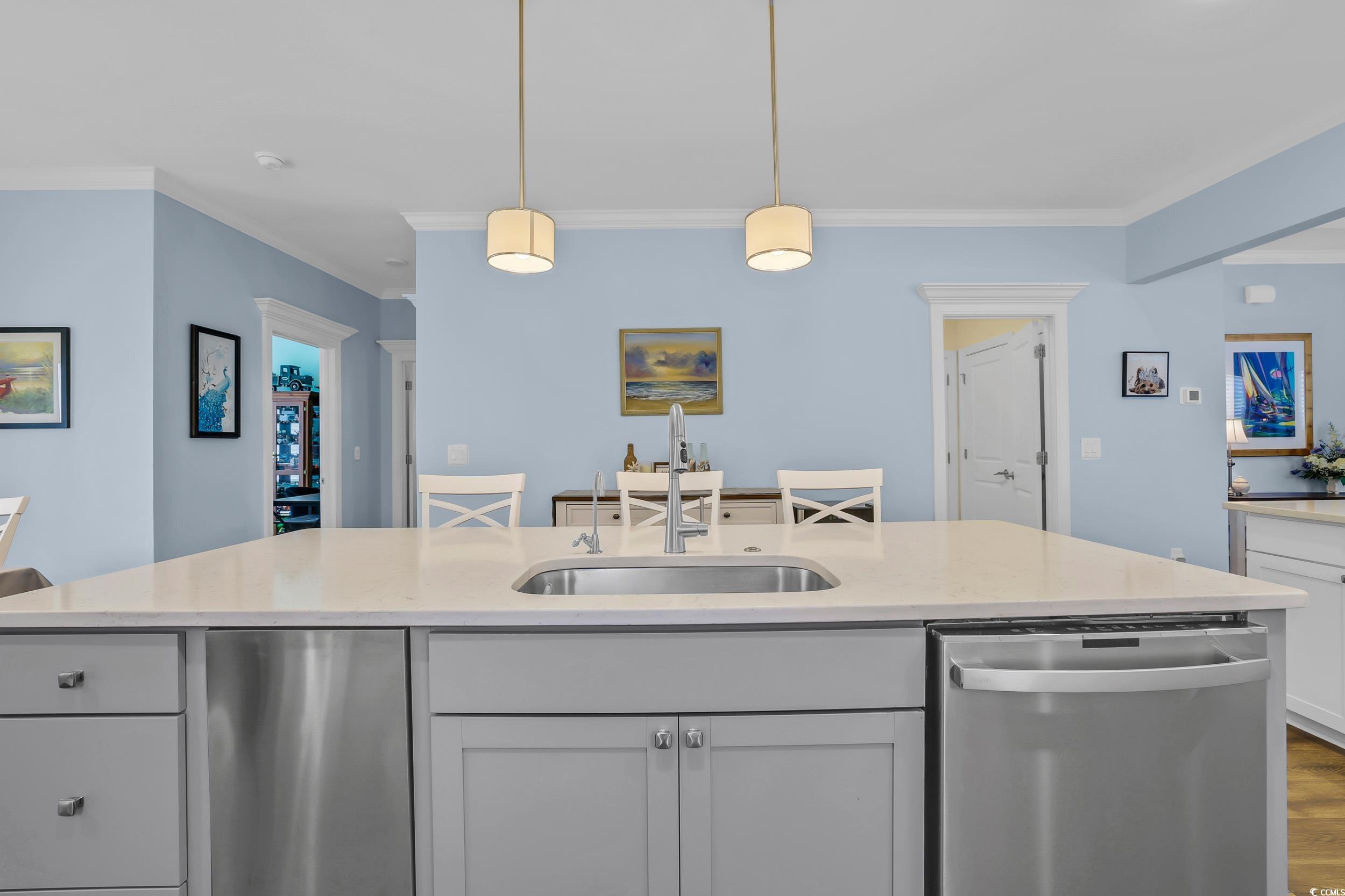 Kitchen featuring dishwasher, a sink, crown molding, hanging light fixtures, and wood finished floors