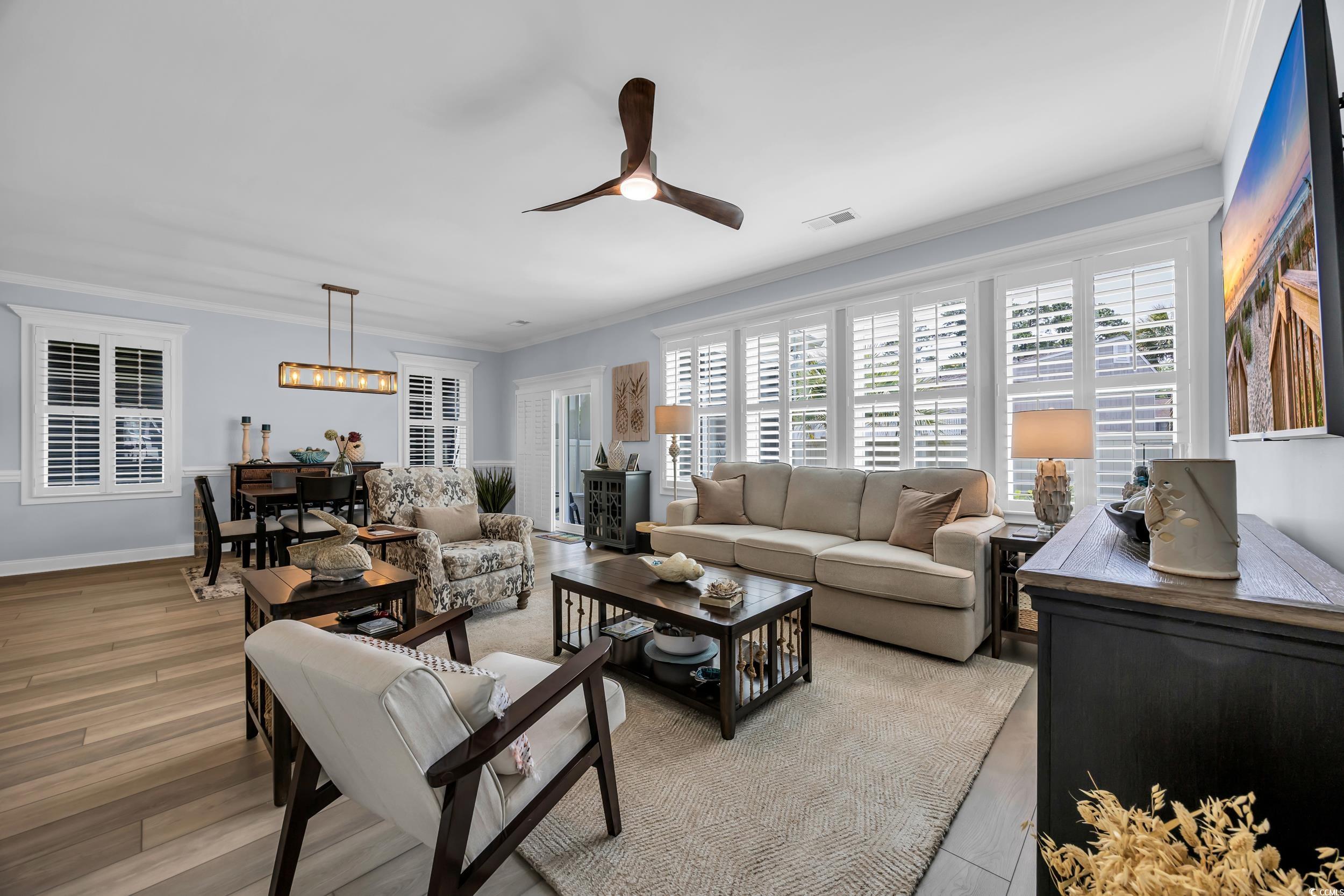 Living room featuring crown molding, a ceiling fan, light wood-style floors, and baseboards