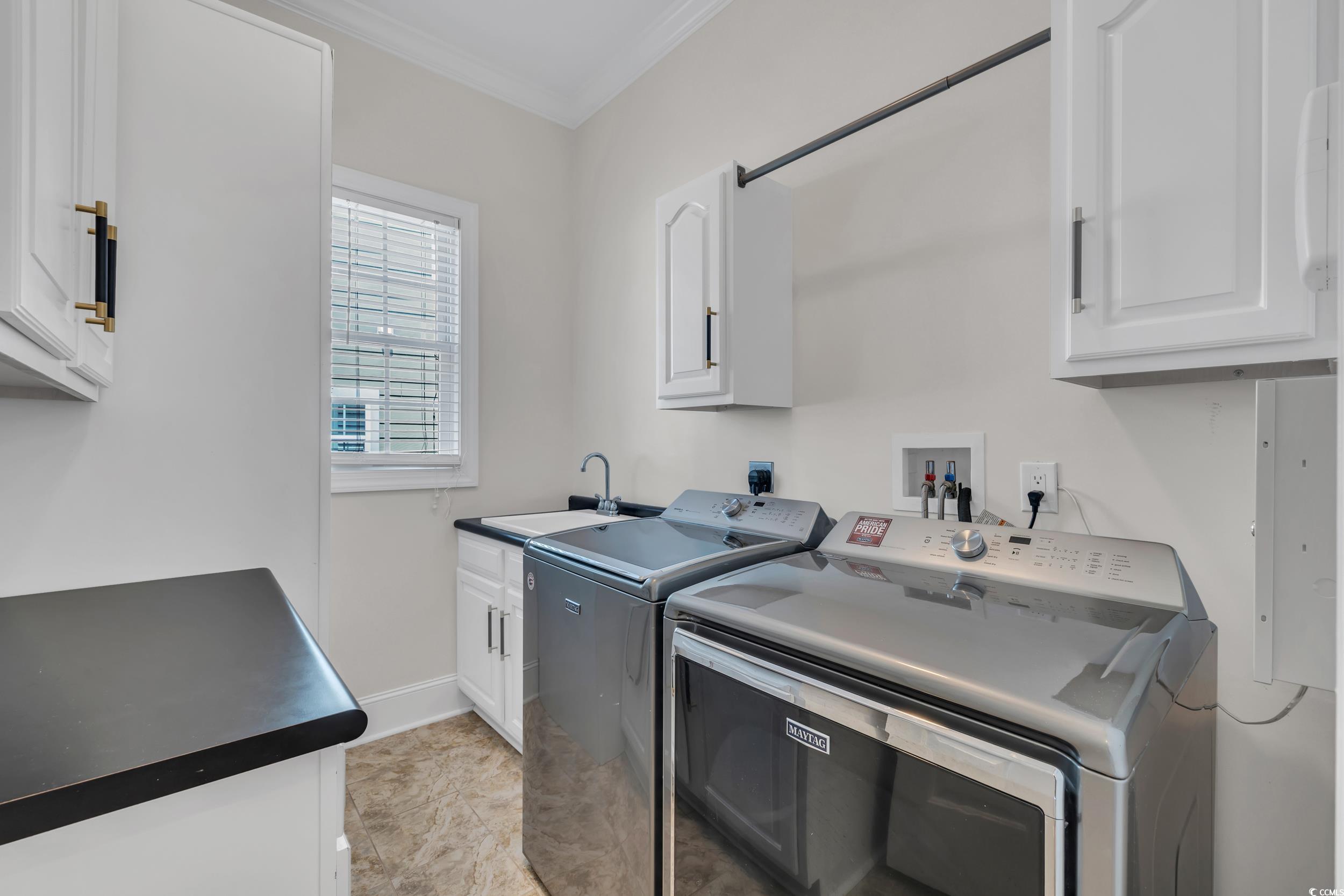 Laundry room featuring cabinet space, independent washer and dryer, ornamental molding, and baseboards